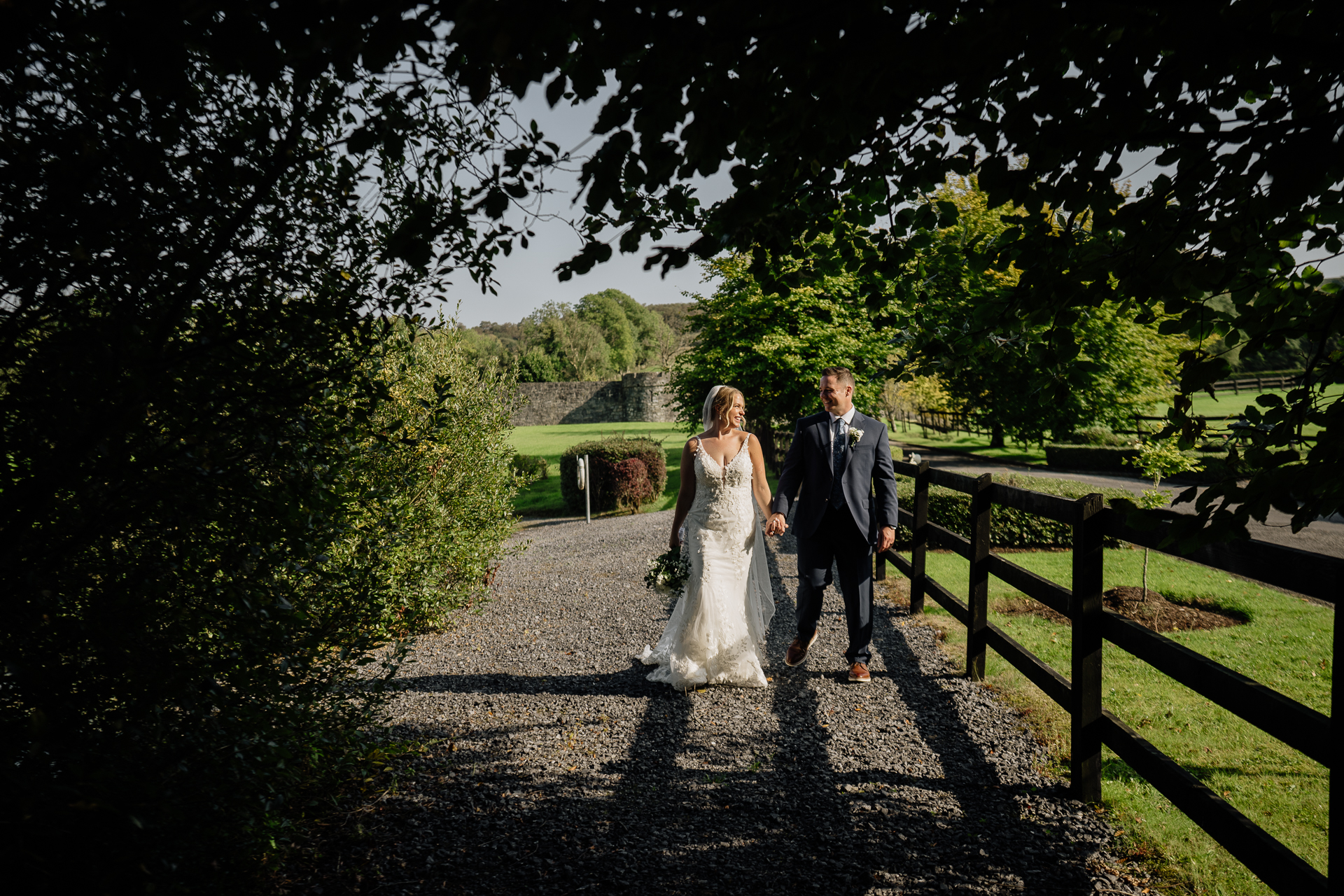 A man and woman walking down a path with trees on either side