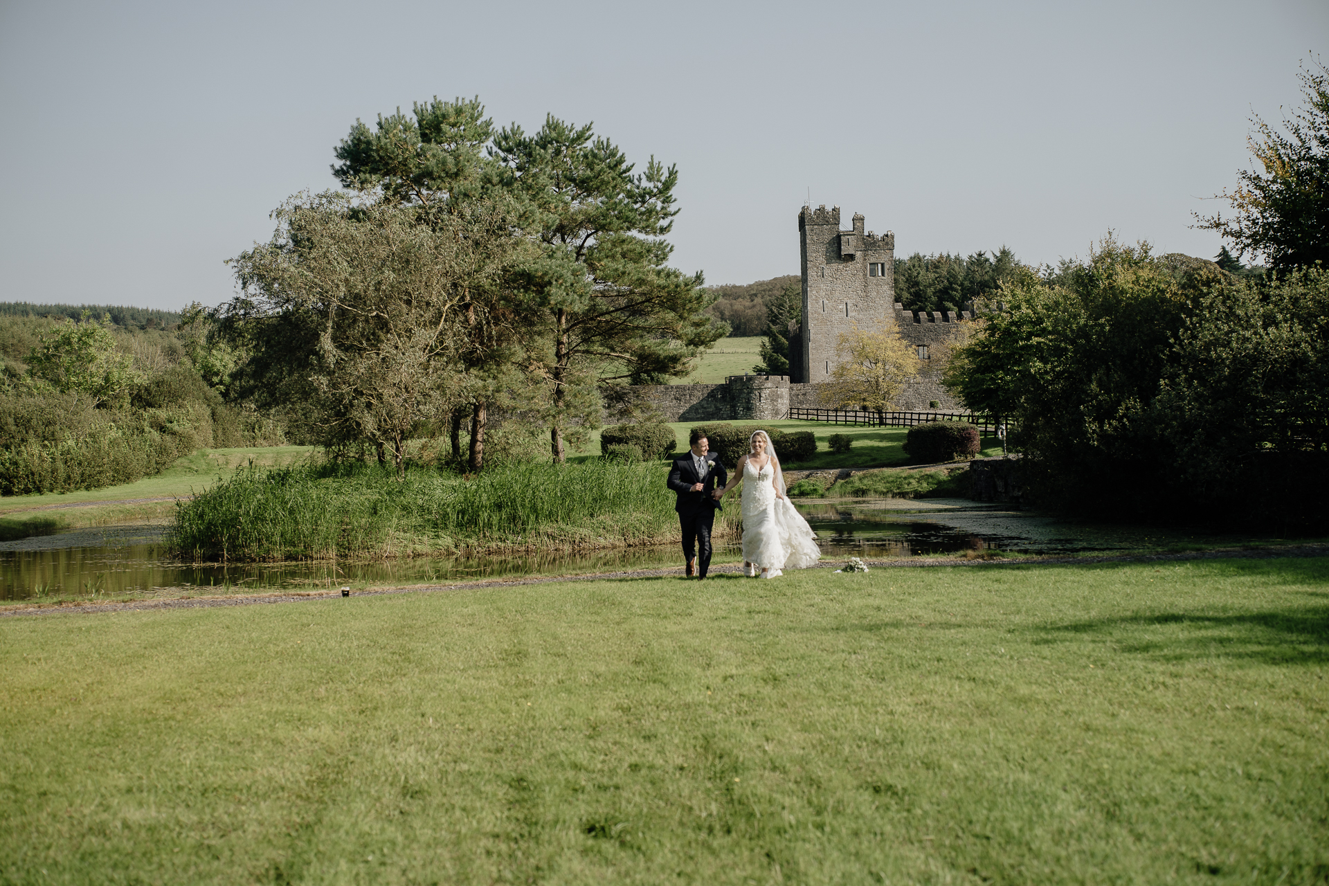 A bride and groom kissing in a field with a castle in the background