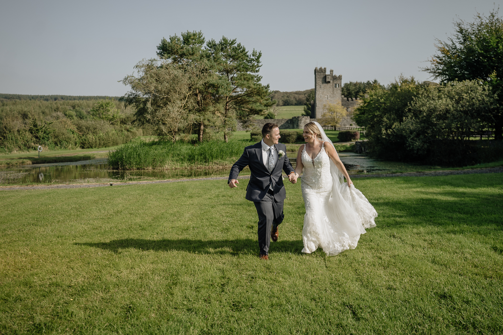 A man and woman walking in a field with a castle in the background