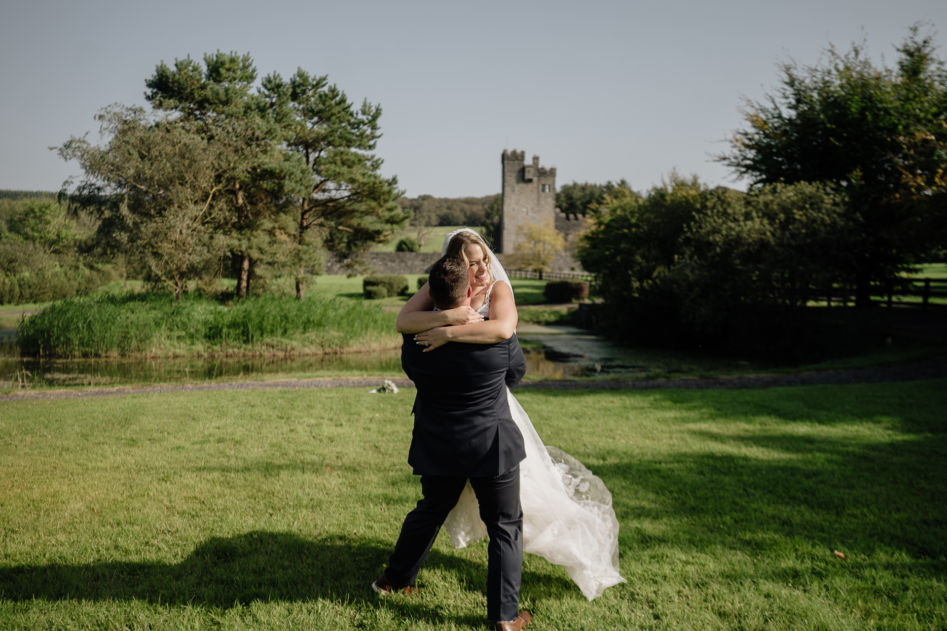 A man and woman kissing in a field with a castle in the background