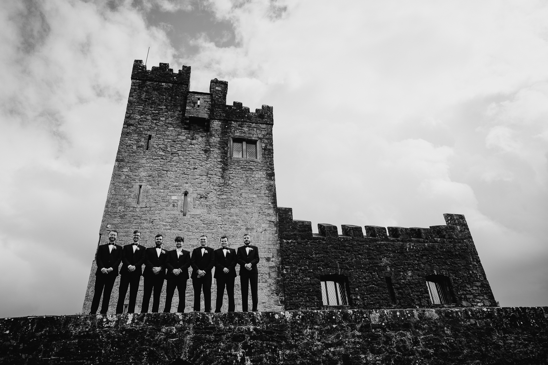 A group of people standing on a stone wall in front of a building