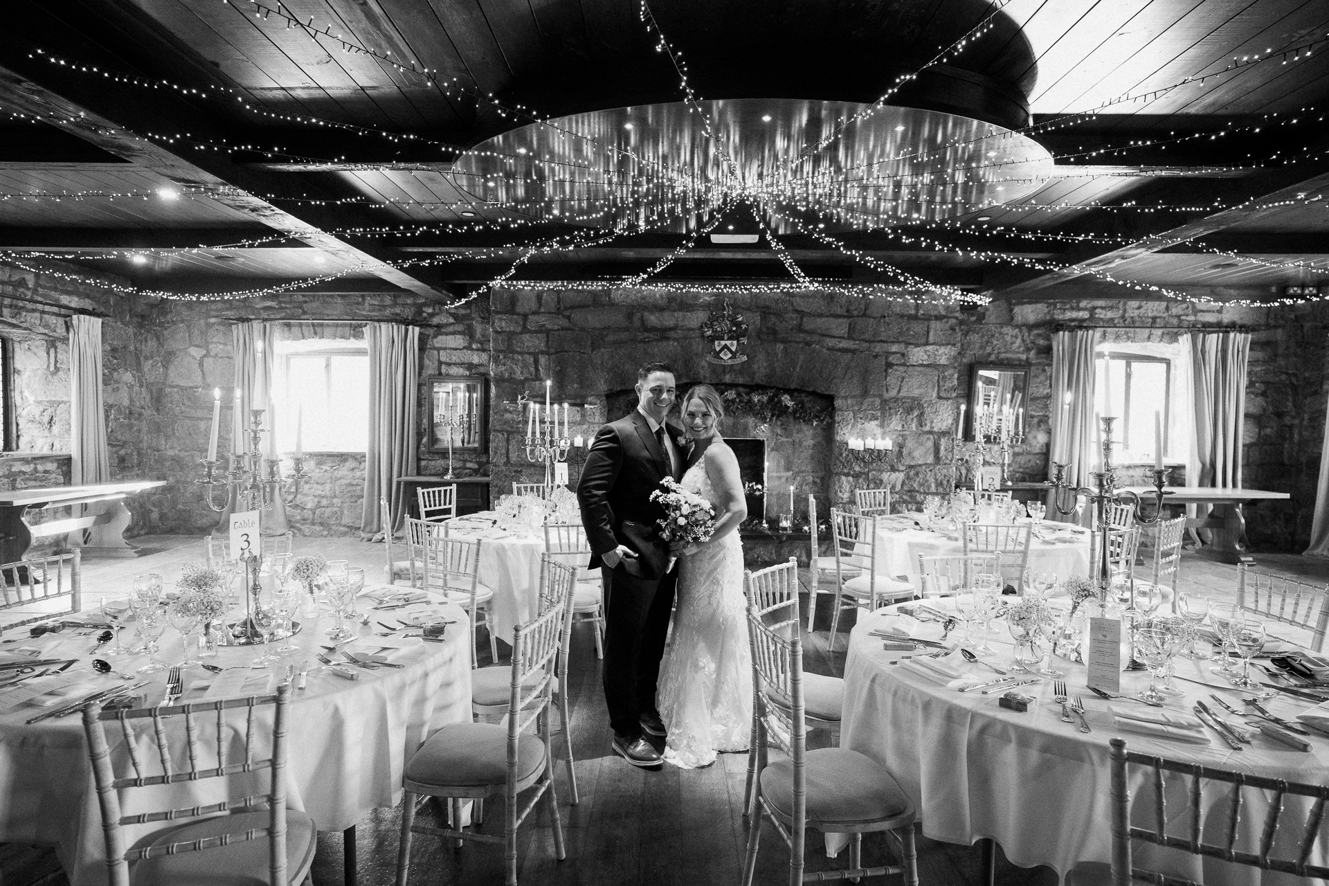 A man and woman standing in a room with tables and chairs