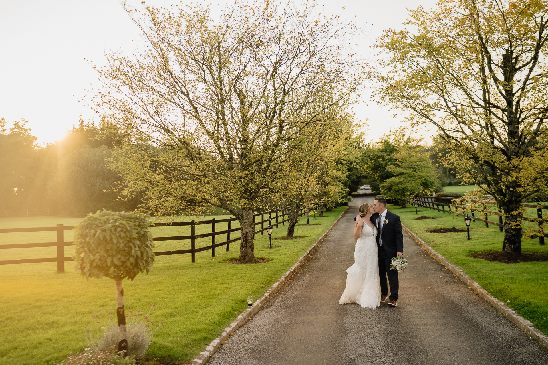 A man and woman walking down a path with trees on either side