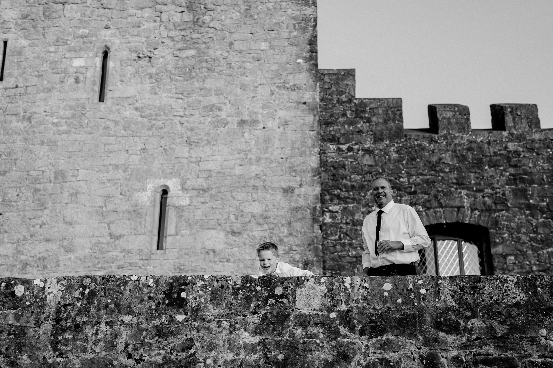 A person and a boy sitting on a wall