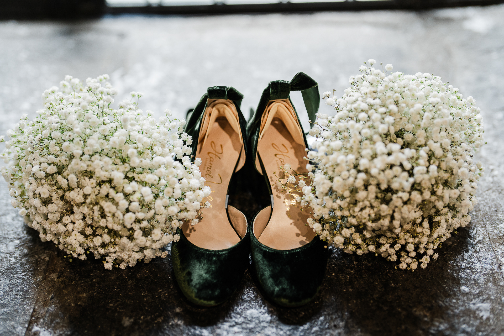 A pair of feet in black shoes next to white flowers