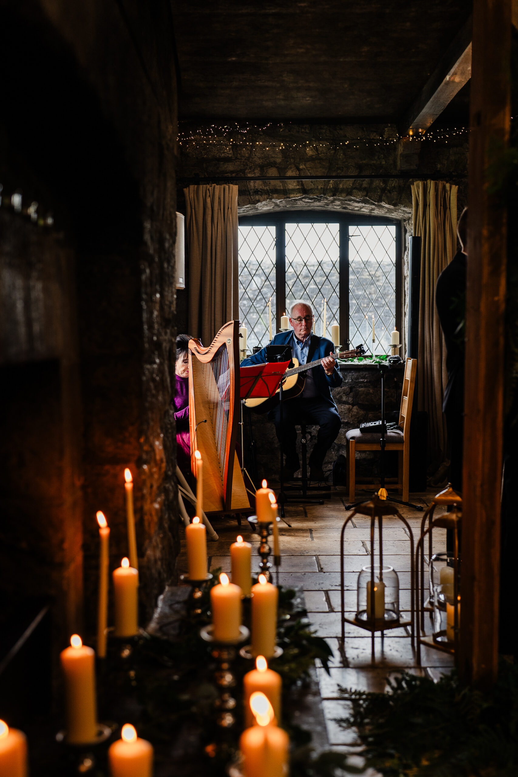 A person playing an instrument in a room with many candles