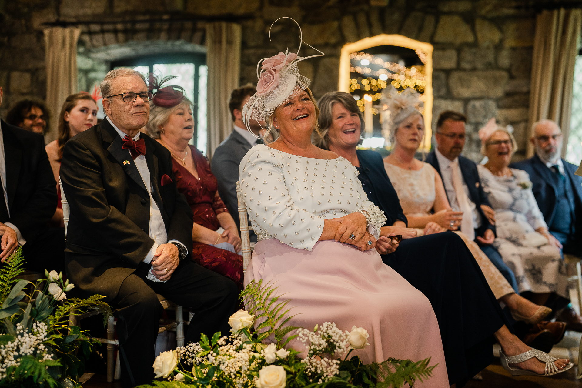 A bride and groom sitting on a bench in front of a crowd