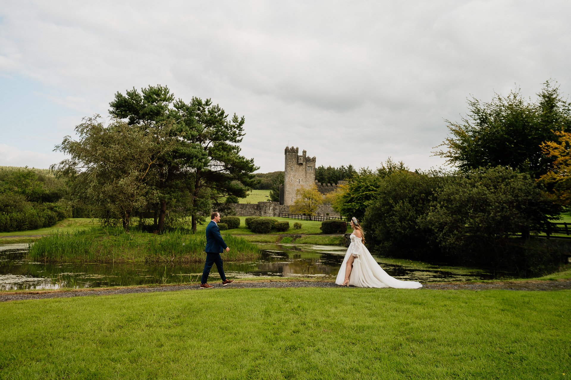 A man and woman walking in a park with a castle in the background