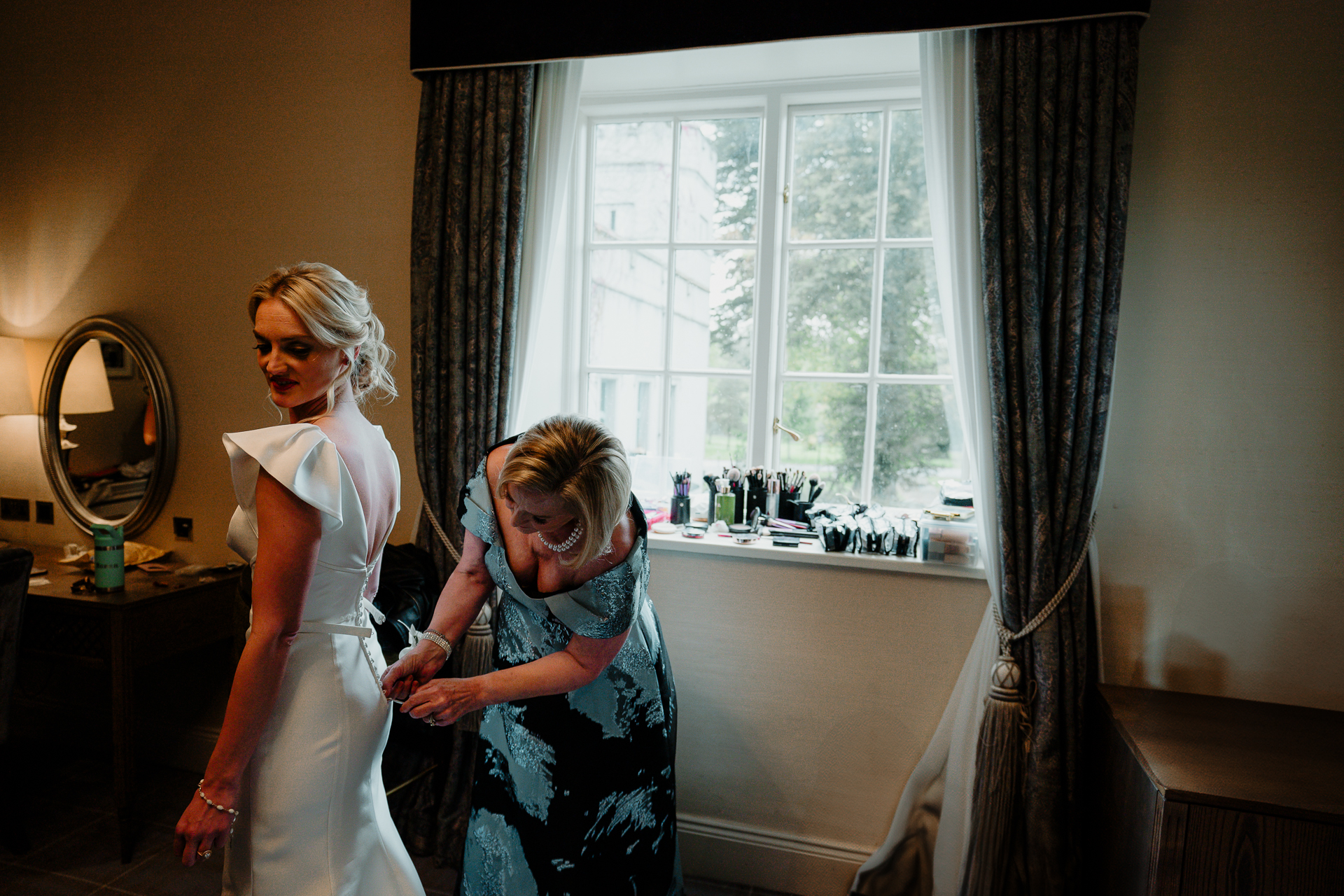 A person and a girl in a room with a window and curtains