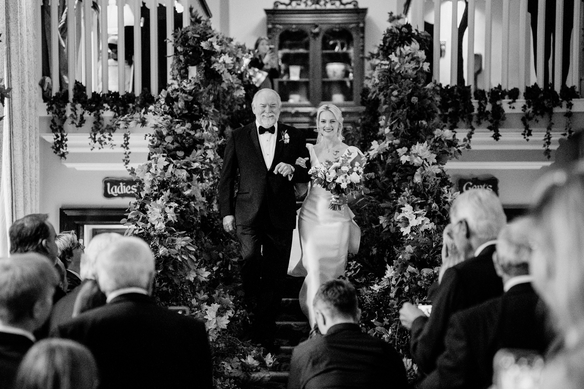 A man and woman walking down a hall with a crowd watching