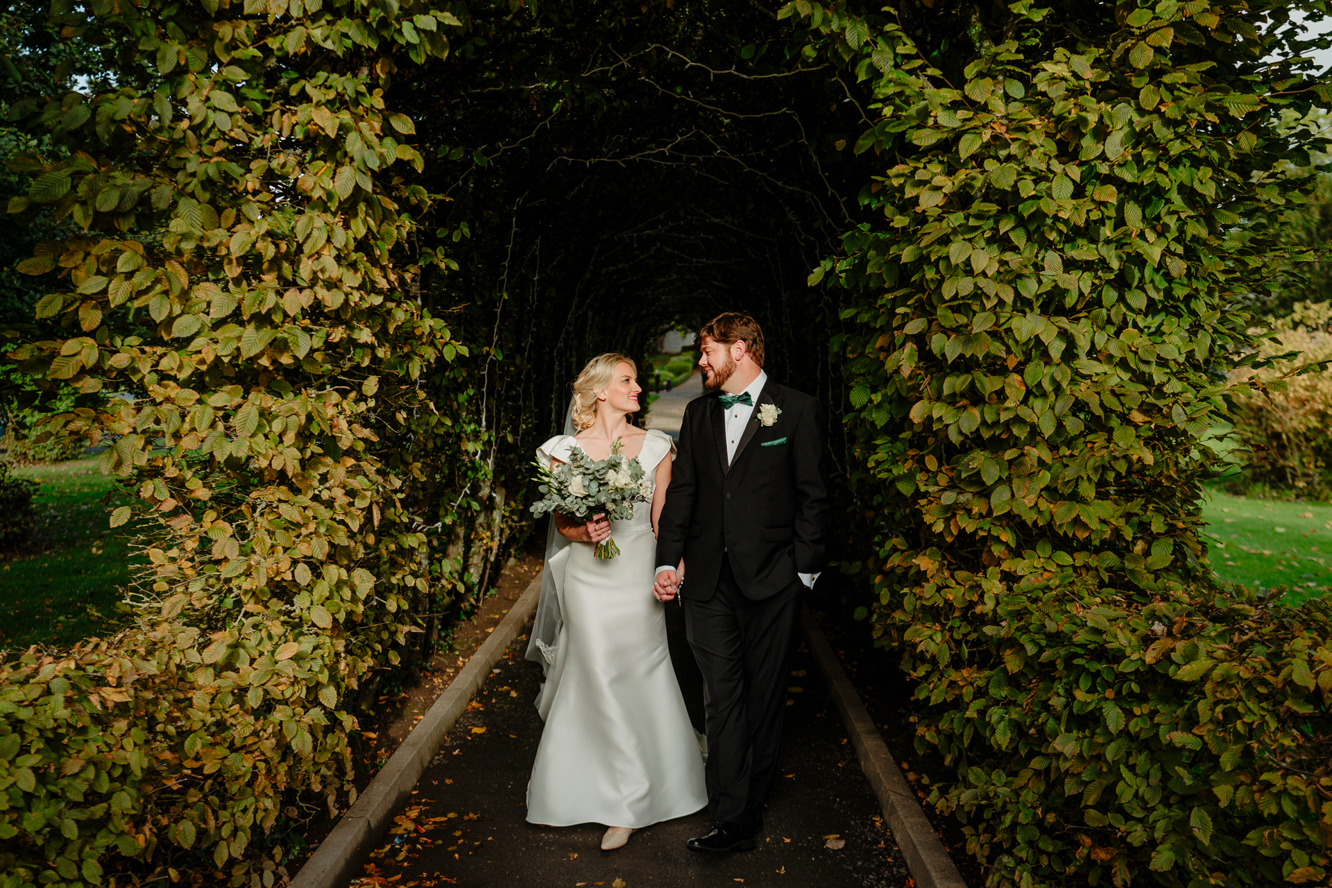 A man and woman walking down a path with plants and trees