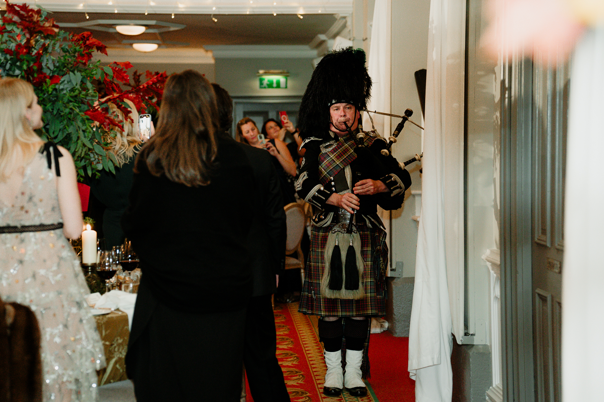 A person in a garment playing a guitar in a room with other people