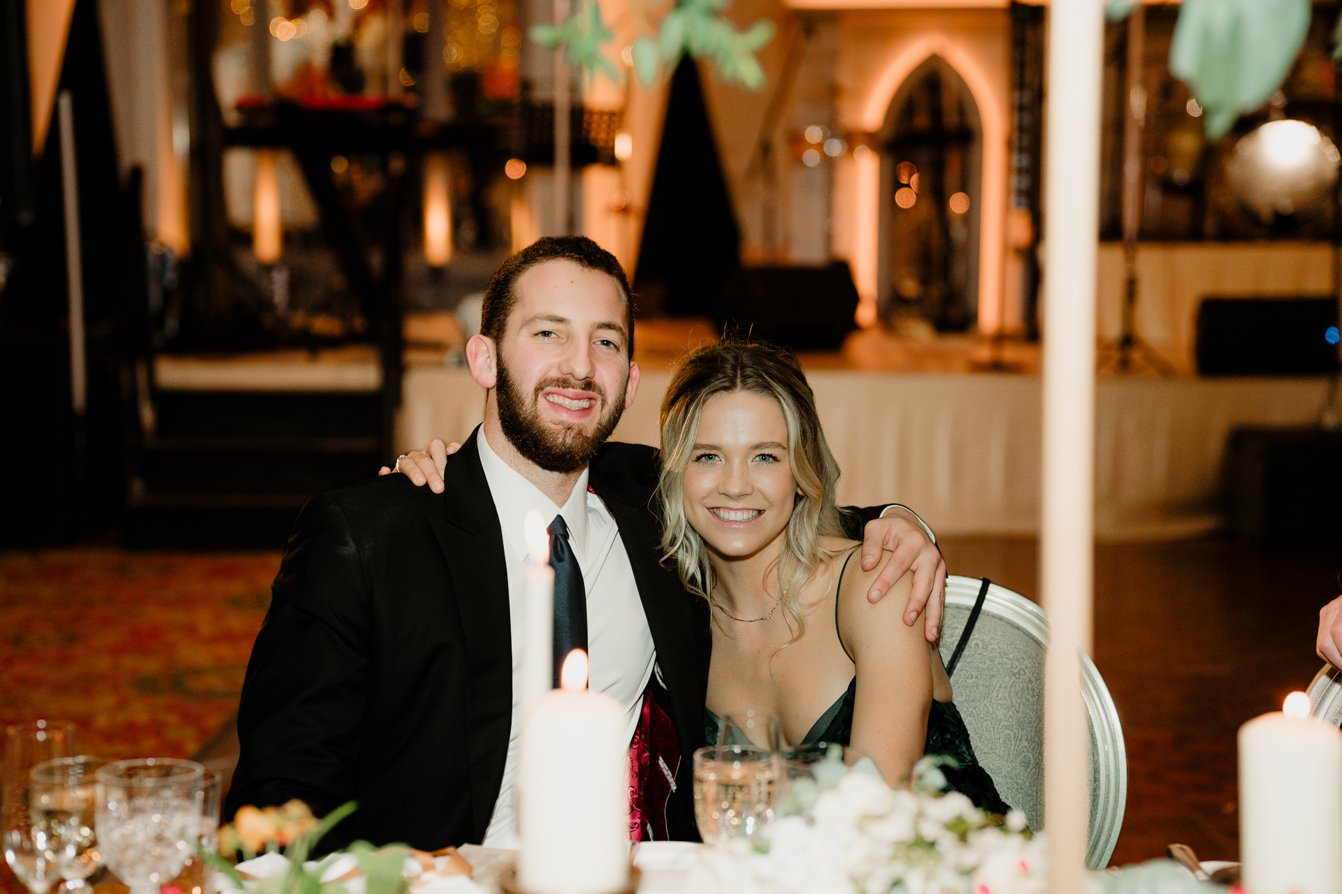 A man and woman sitting at a table with a candle and glasses