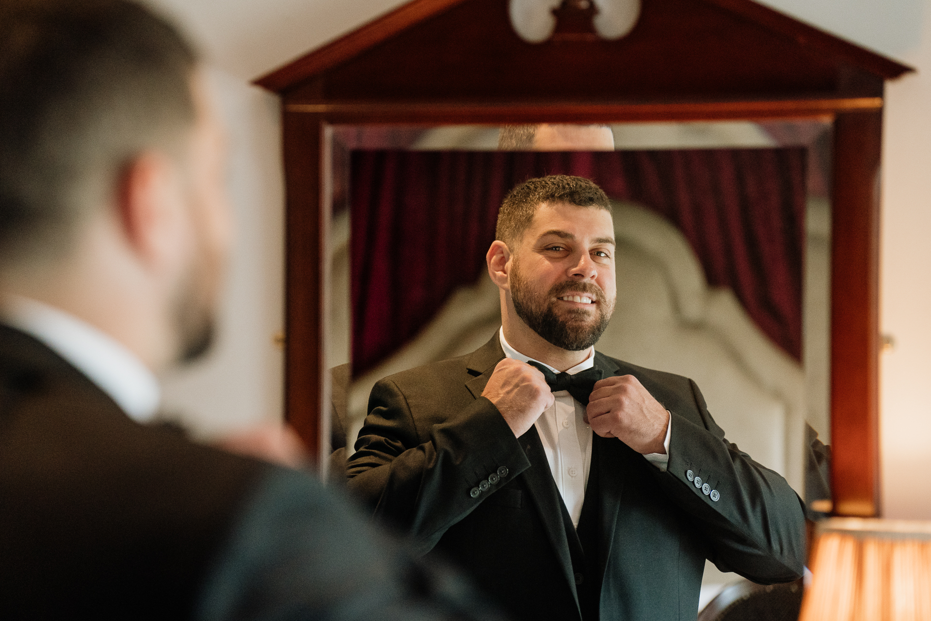 A man in a suit tying his tie