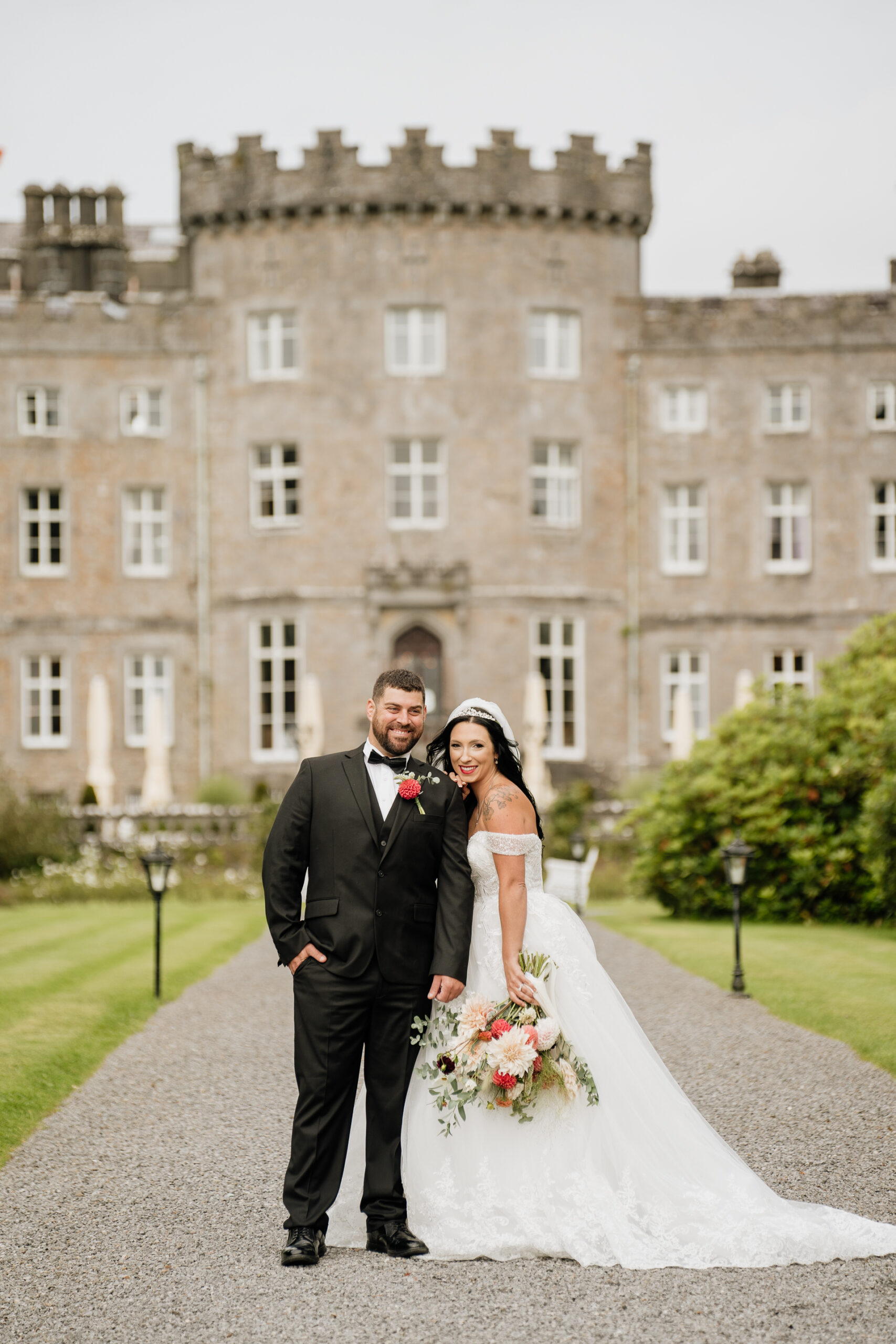 A man and woman posing in front of a large building