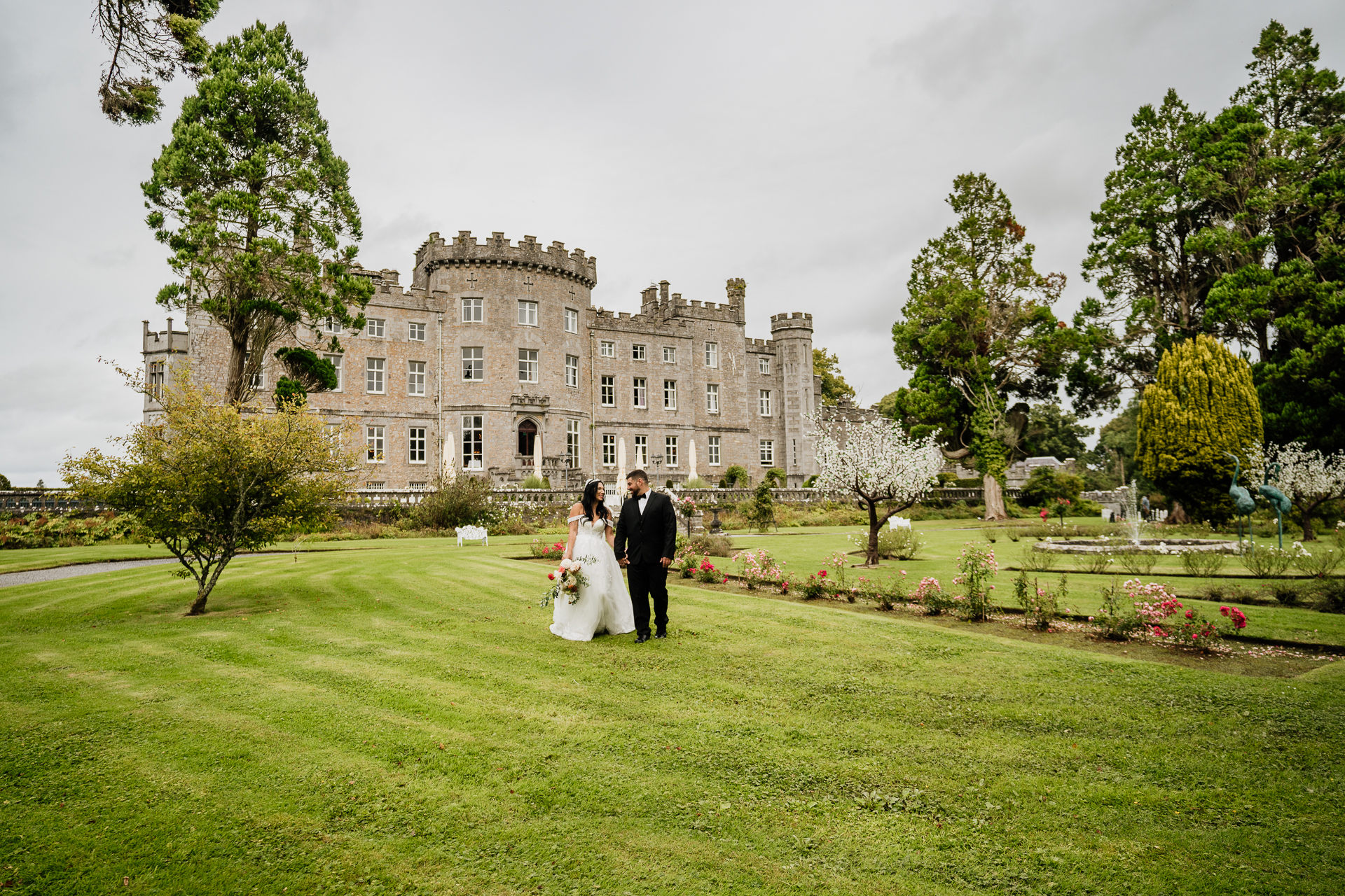 A man and woman in wedding attire walking in front of a large building