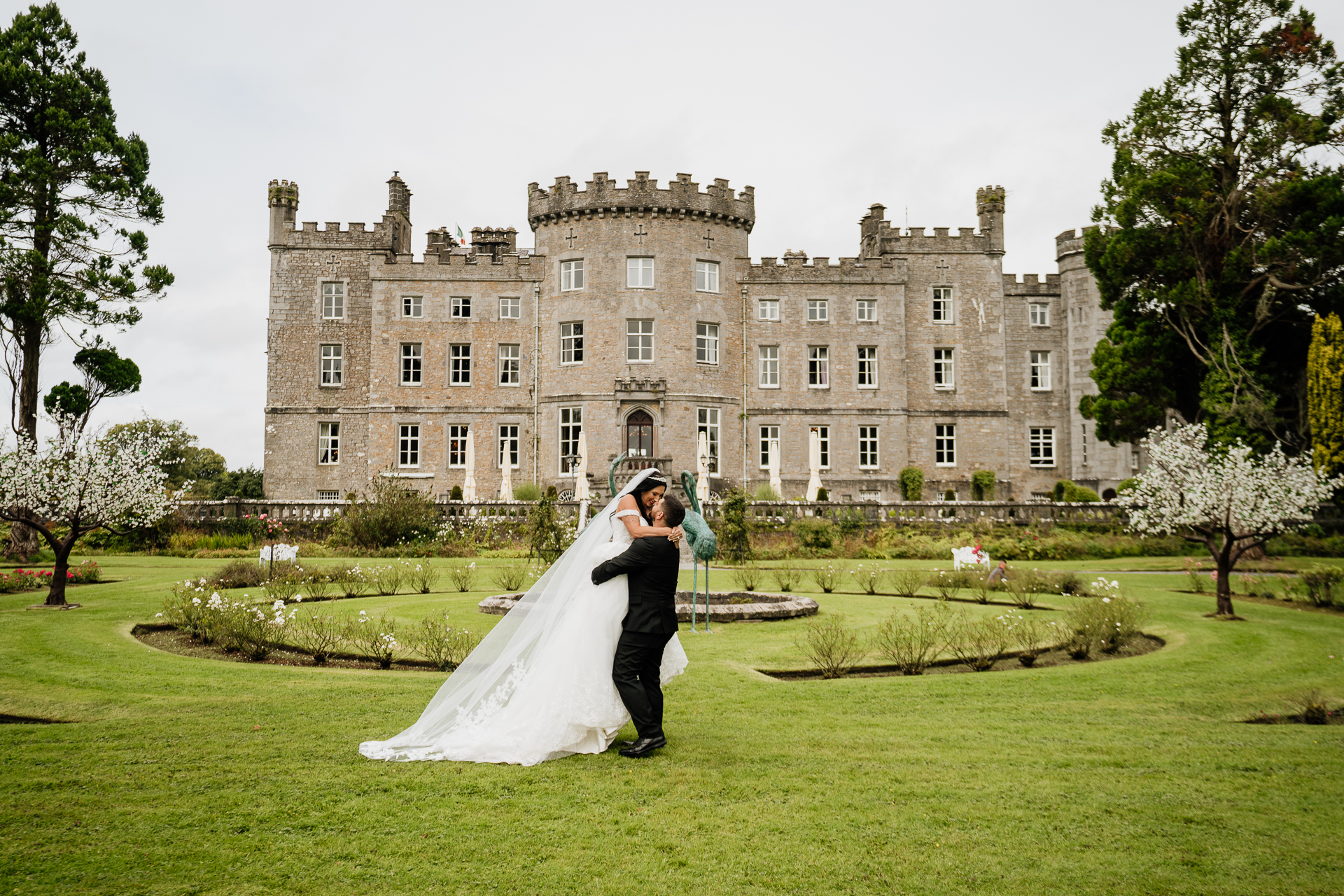 A man and woman kissing in front of a large building