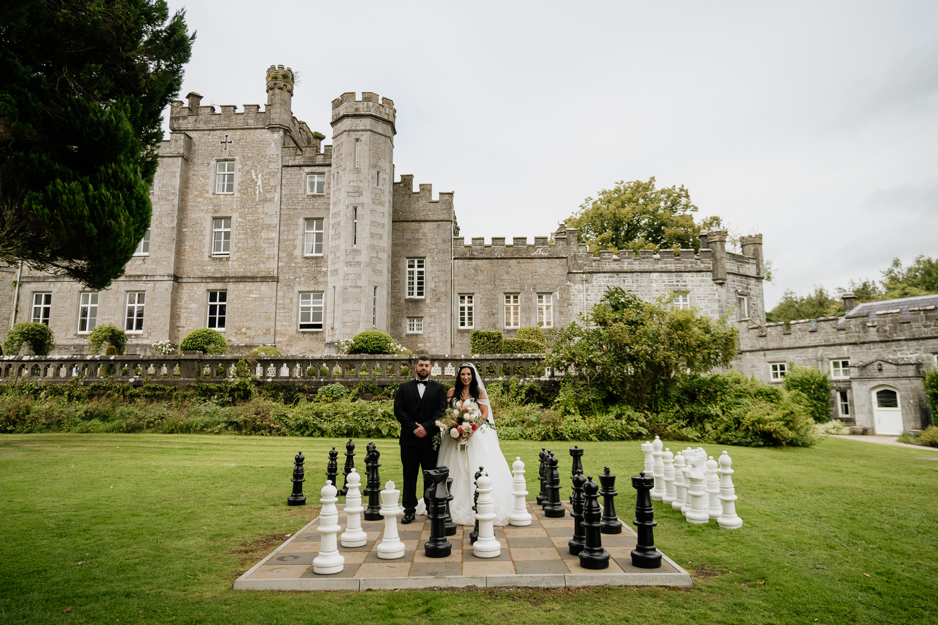 A bride and groom posing in front of a castle