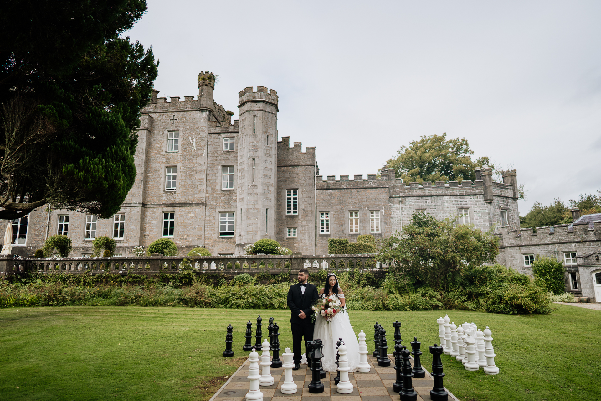 A bride and groom posing in front of a castle