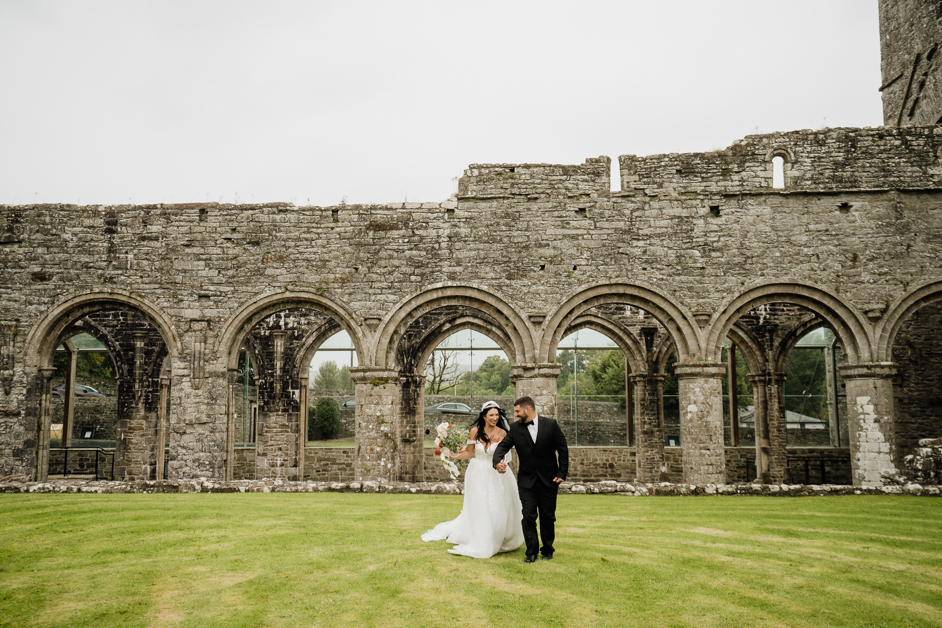 A man and woman in wedding attire in front of a stone building