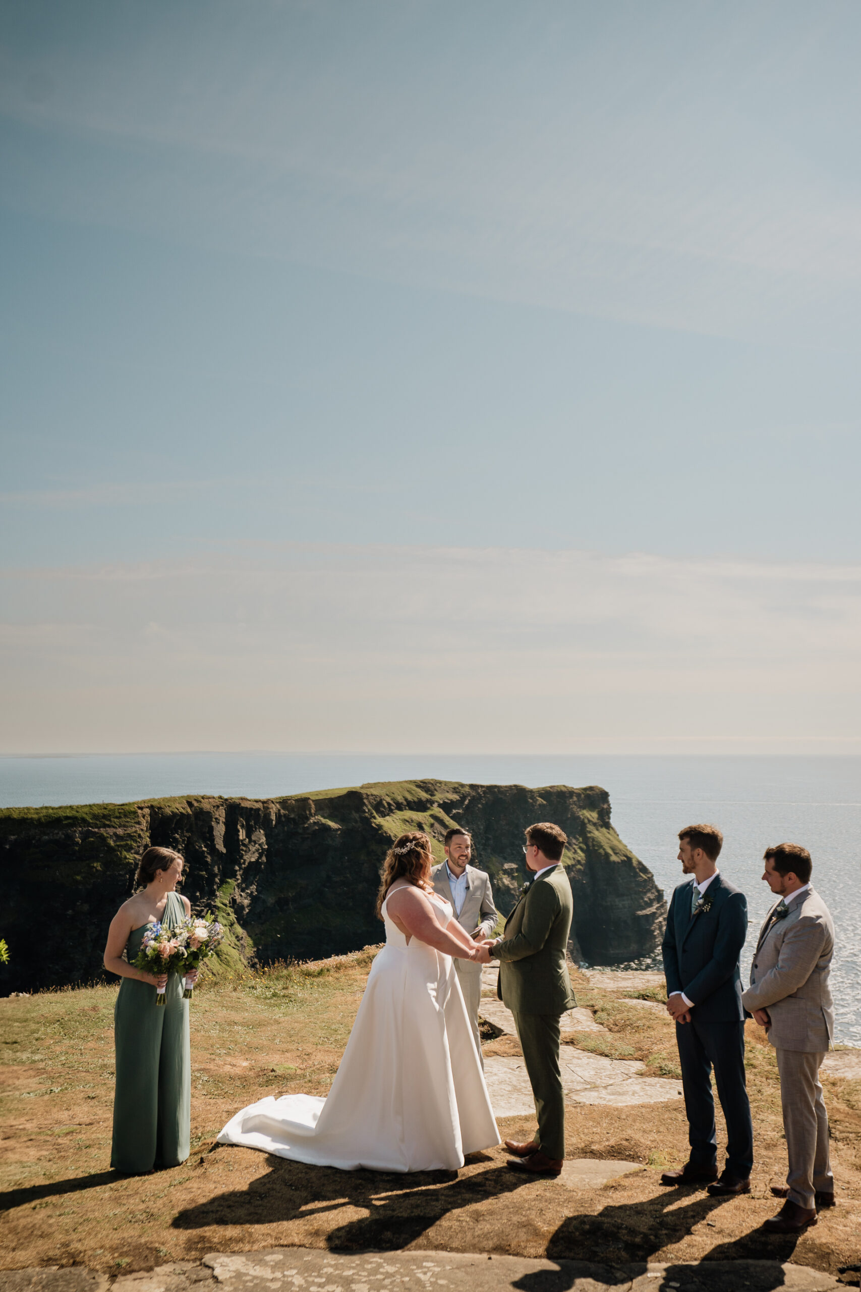 A group of people standing on a hill with a body of water in the background