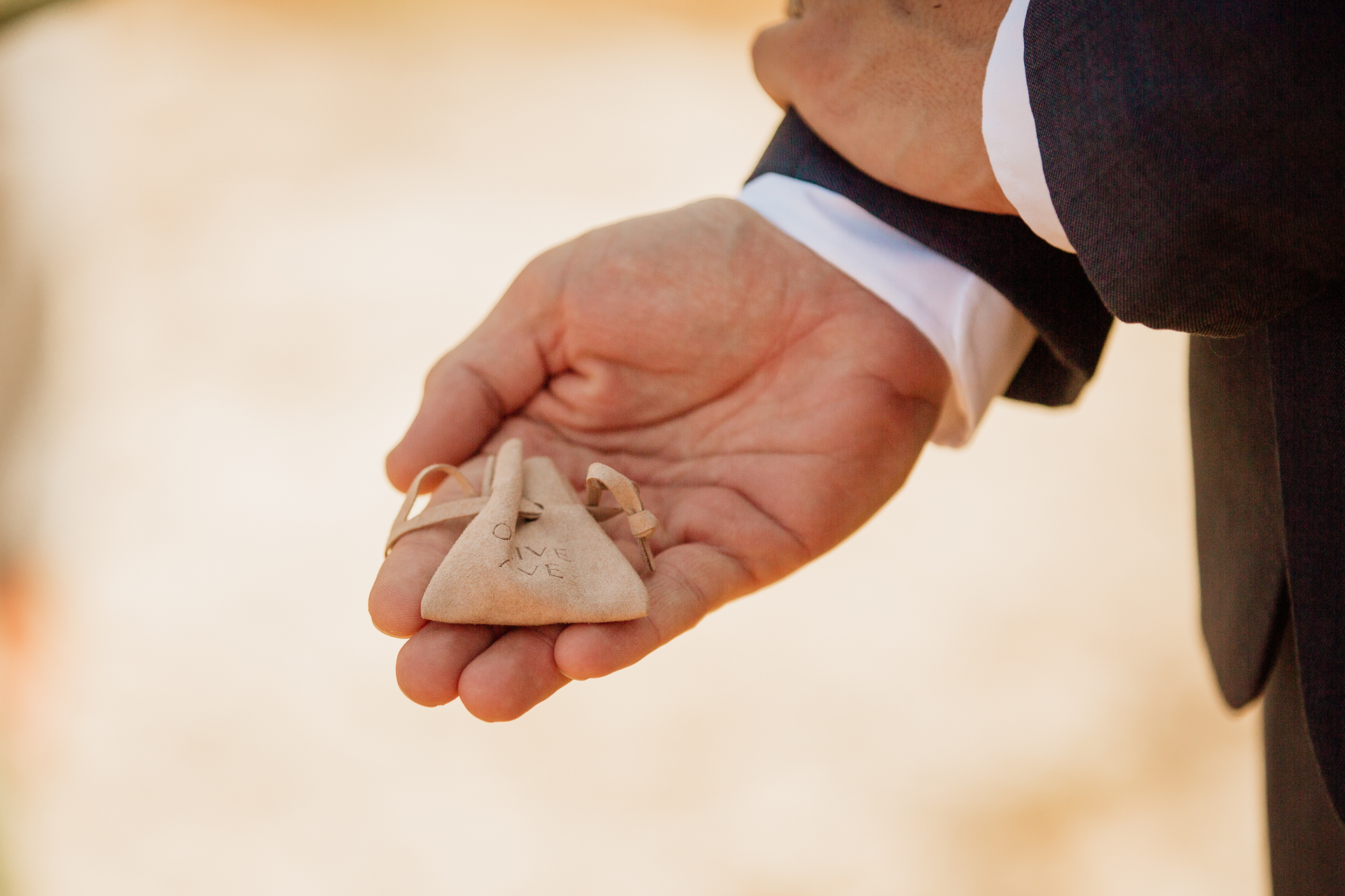 A close-up of hands holding a small gold ring