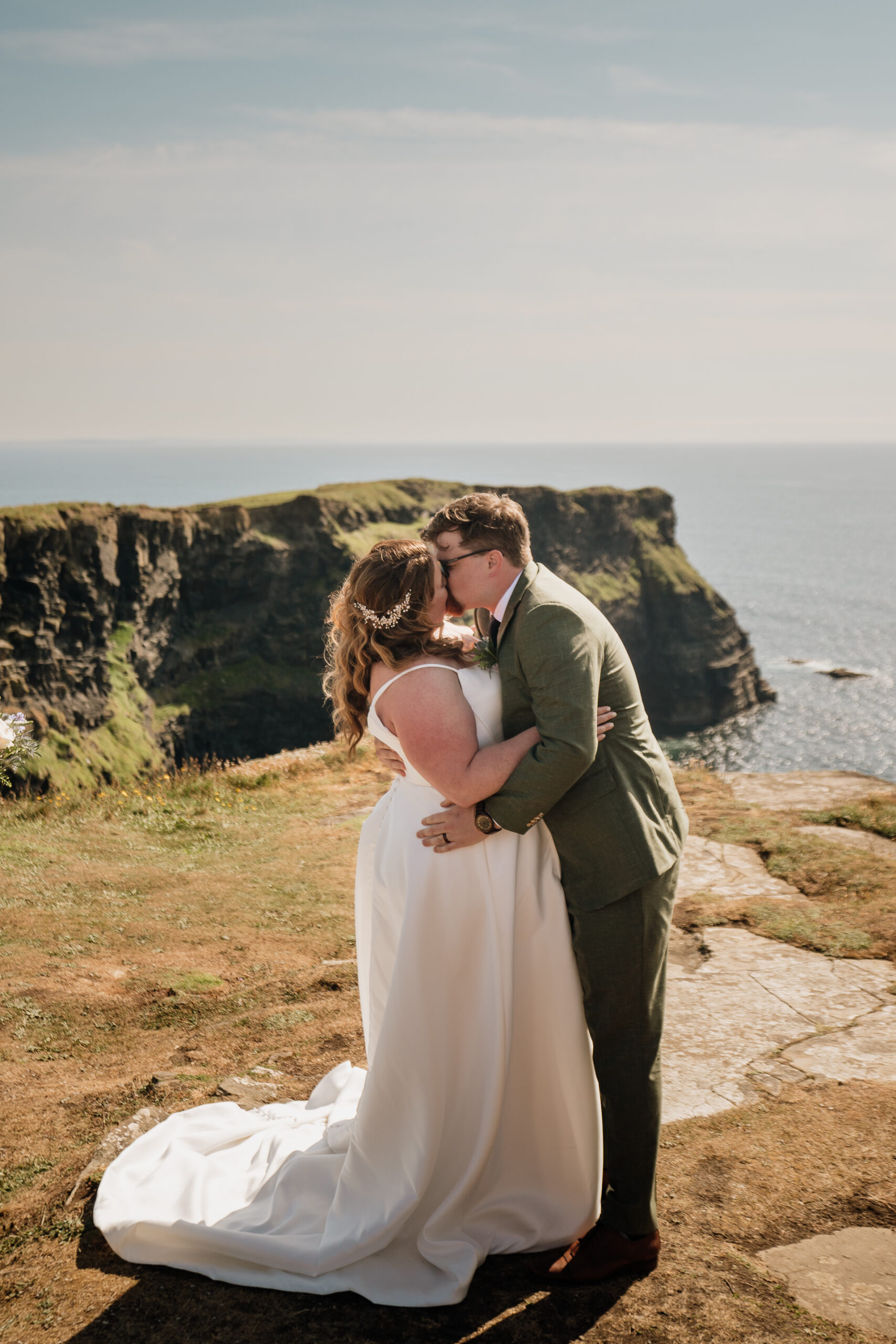 A man and woman posing for a picture on a cliff overlooking the ocean