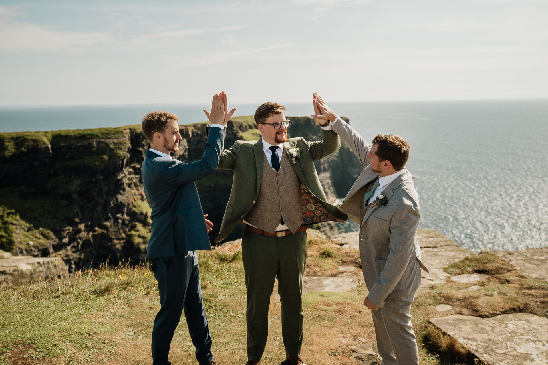 A group of men posing for a picture on a cliff above the ocean