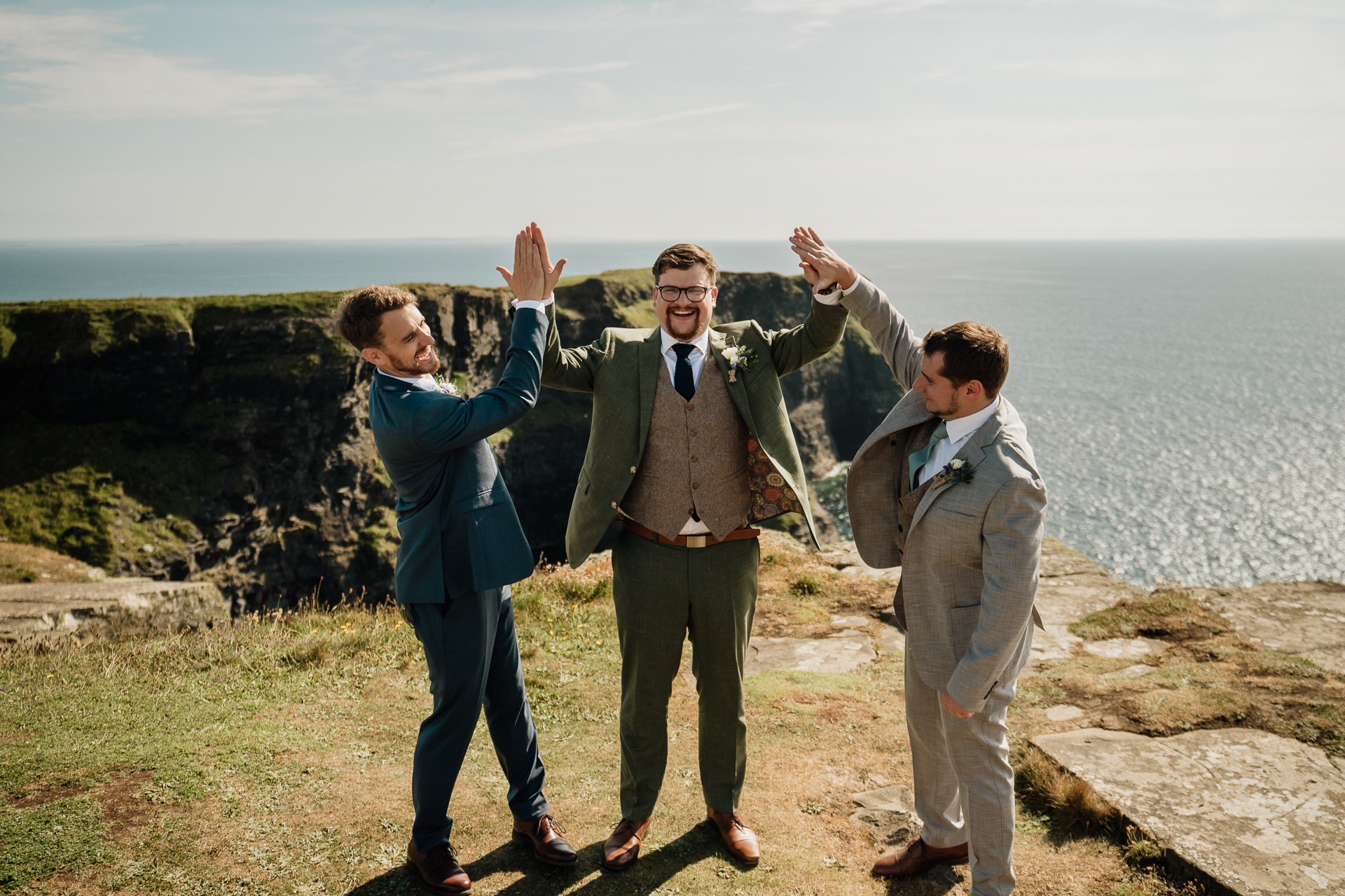 A group of men posing for a picture on a cliff above the ocean