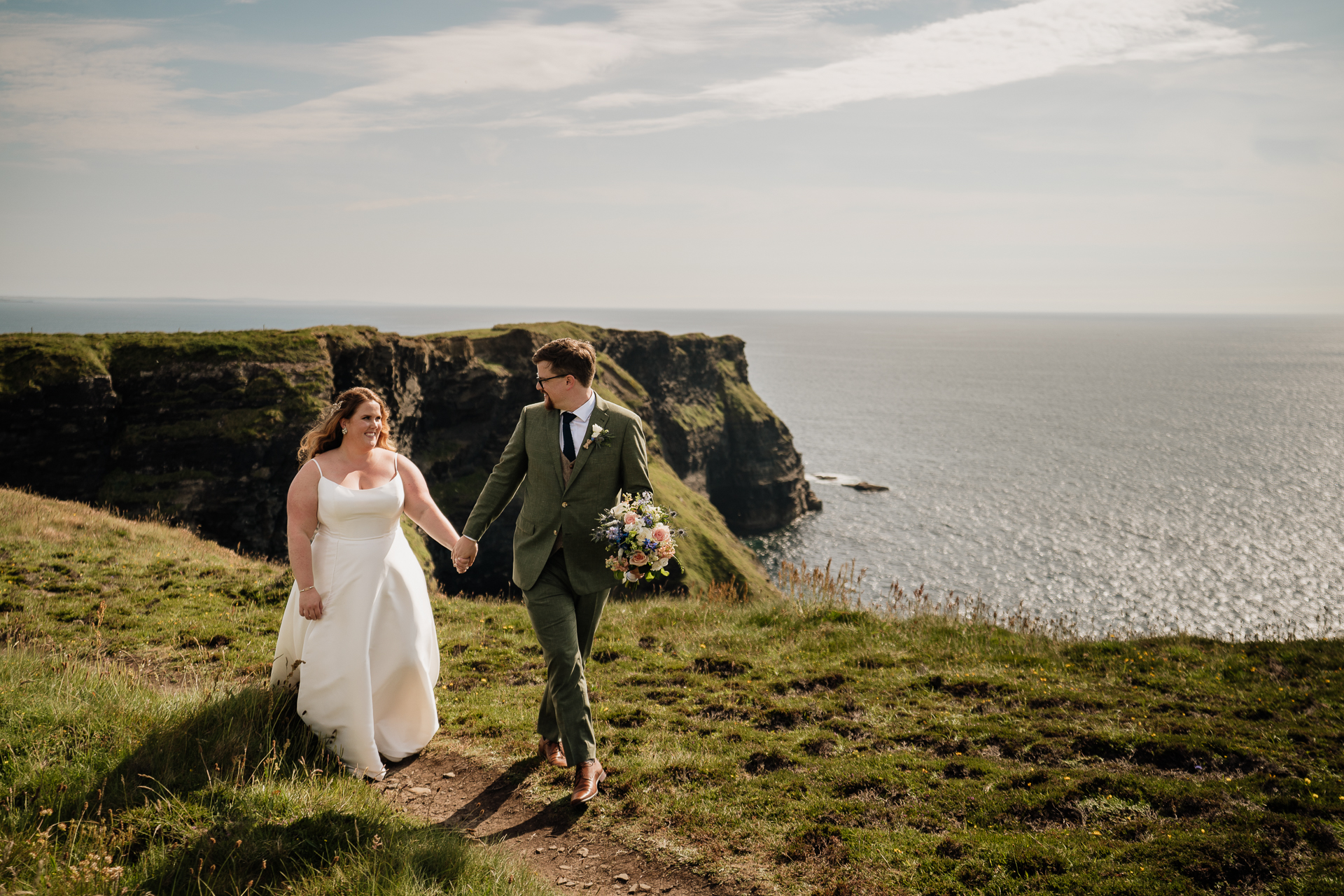 A man and woman walking on a hill by the water