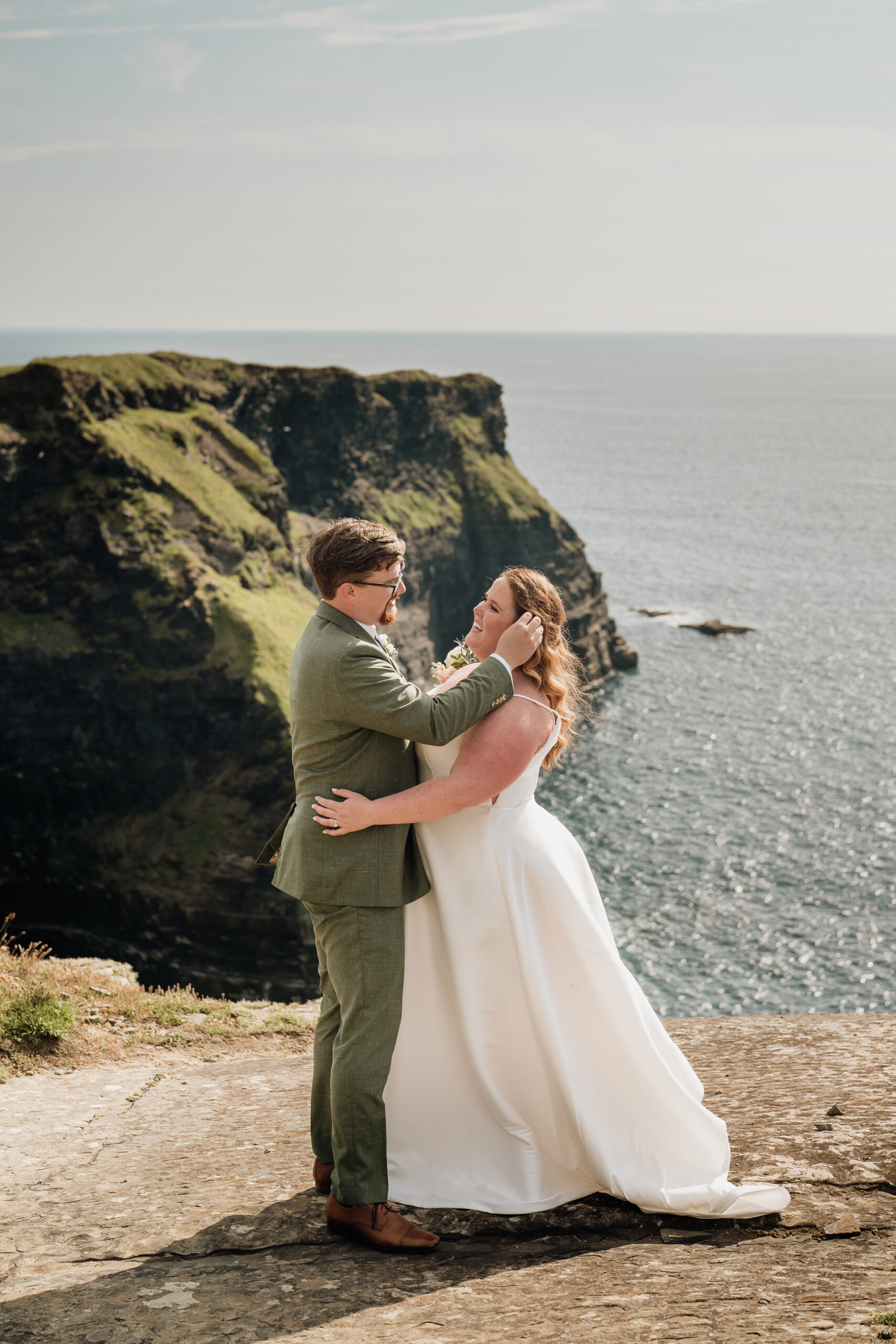 A man and woman kissing on a cliff by the ocean