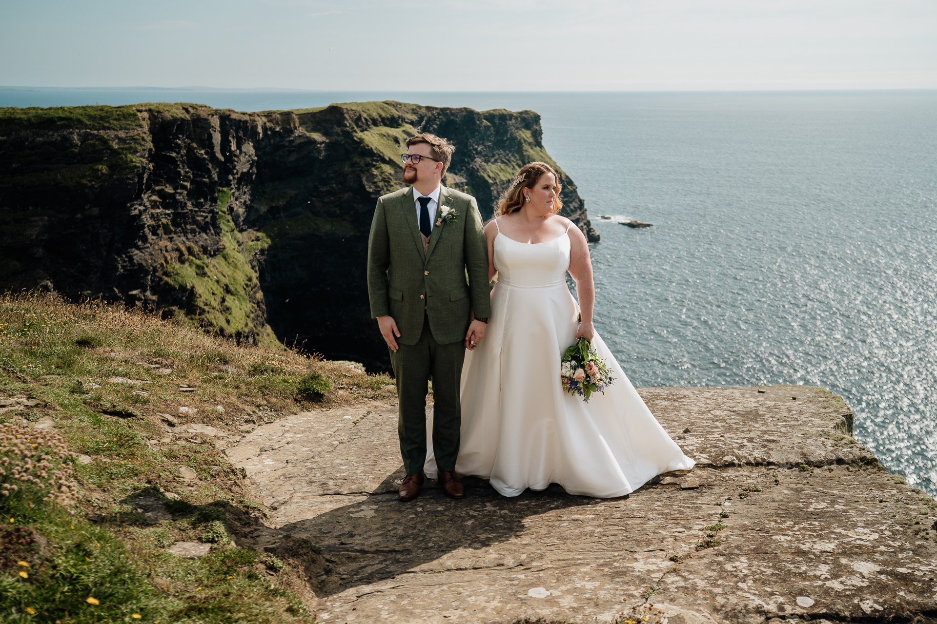 A man and woman posing for a picture on a cliff above water