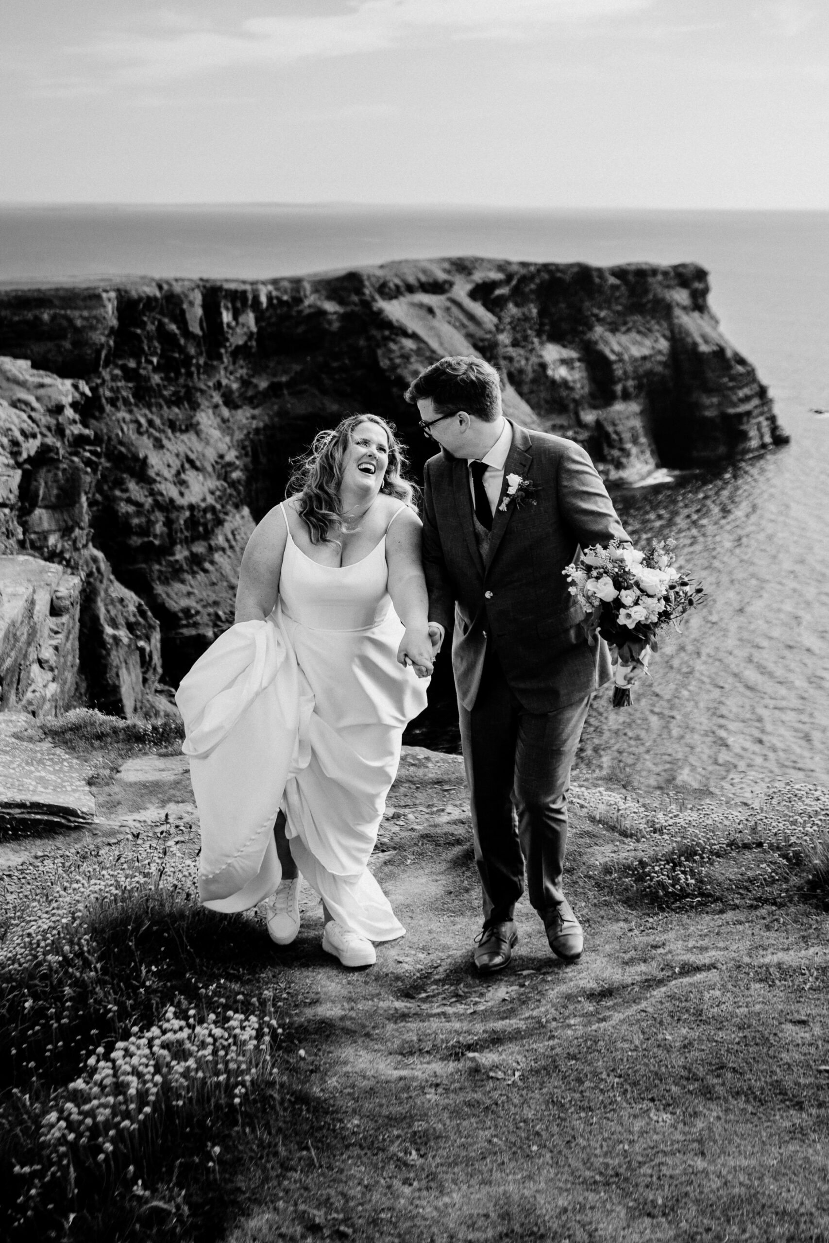 A man and woman walking down a path with flowers on their hands