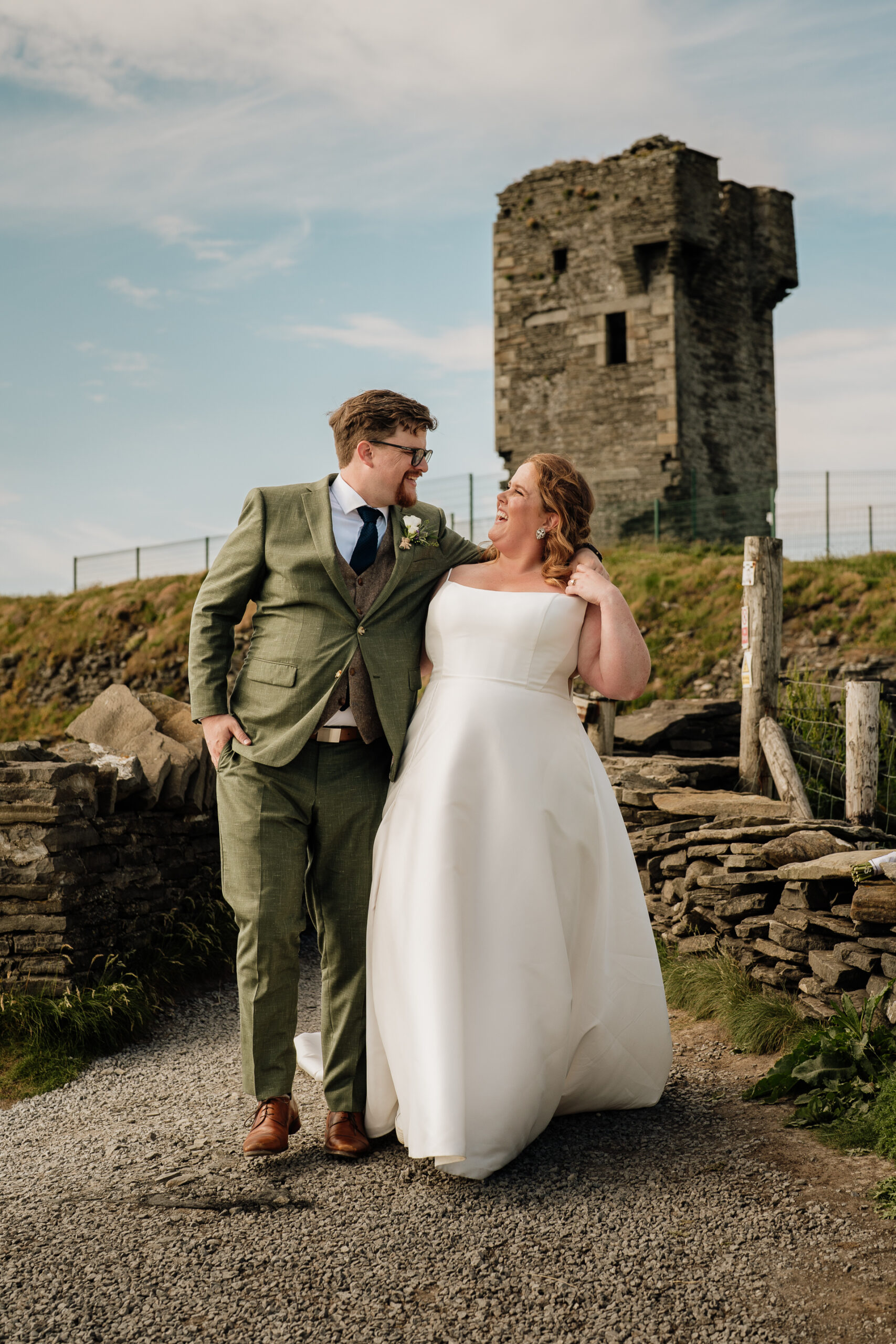 A man and woman posing for a picture in front of a stone building