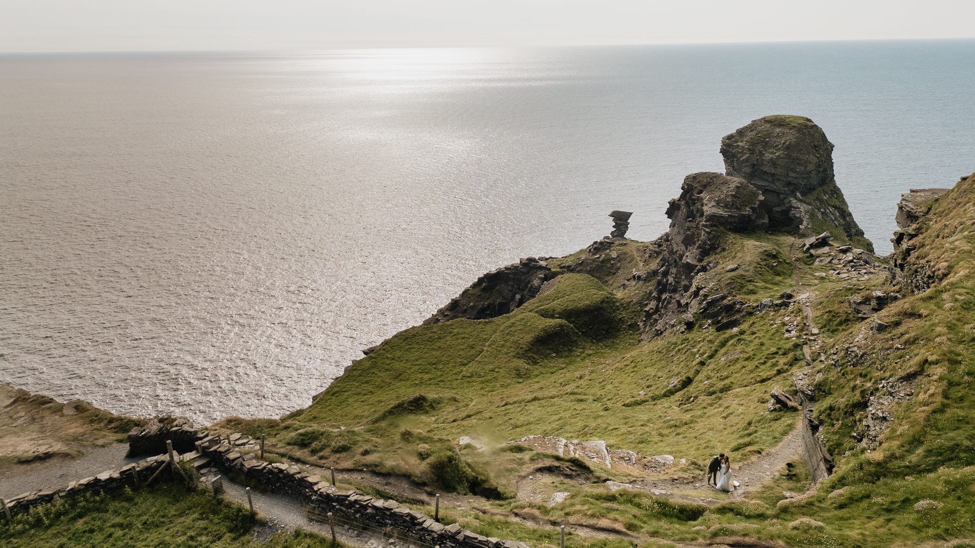 A person standing on a cliff above the ocean