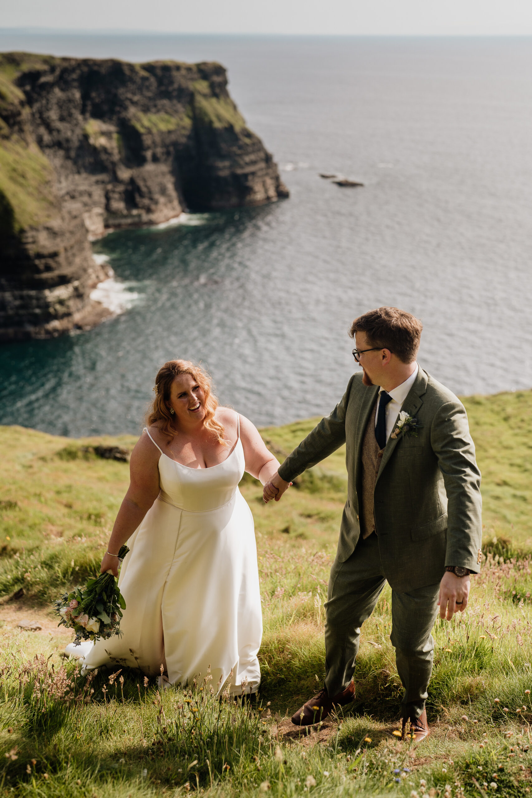 A man and woman walking on a path by a body of water