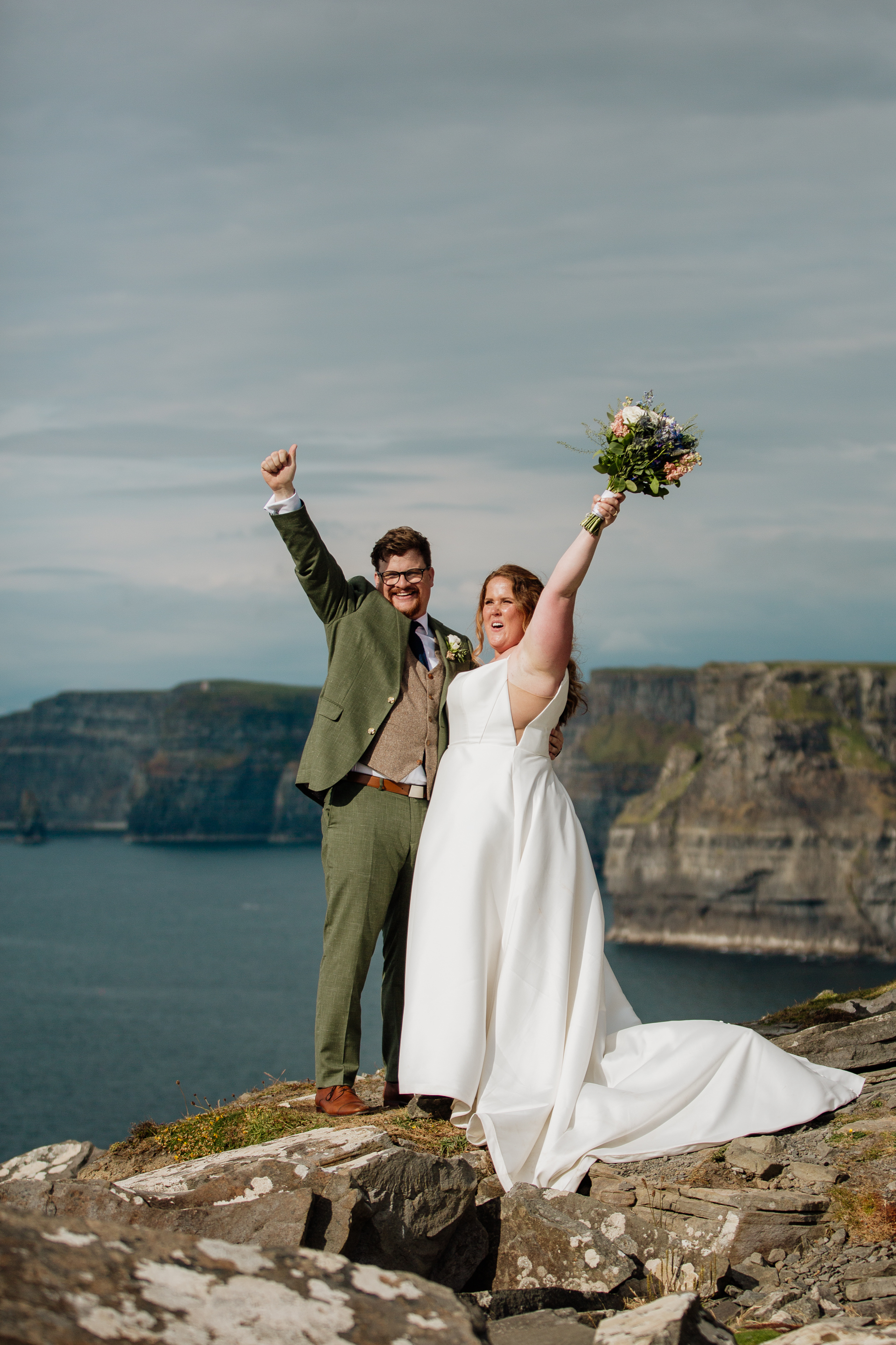 A man and woman posing for a picture on a rocky beach