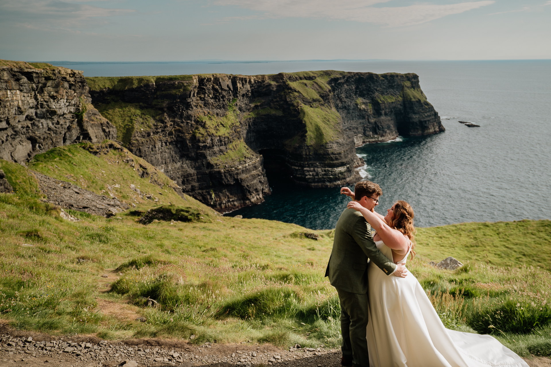 A man and woman kissing on a cliff overlooking the ocean