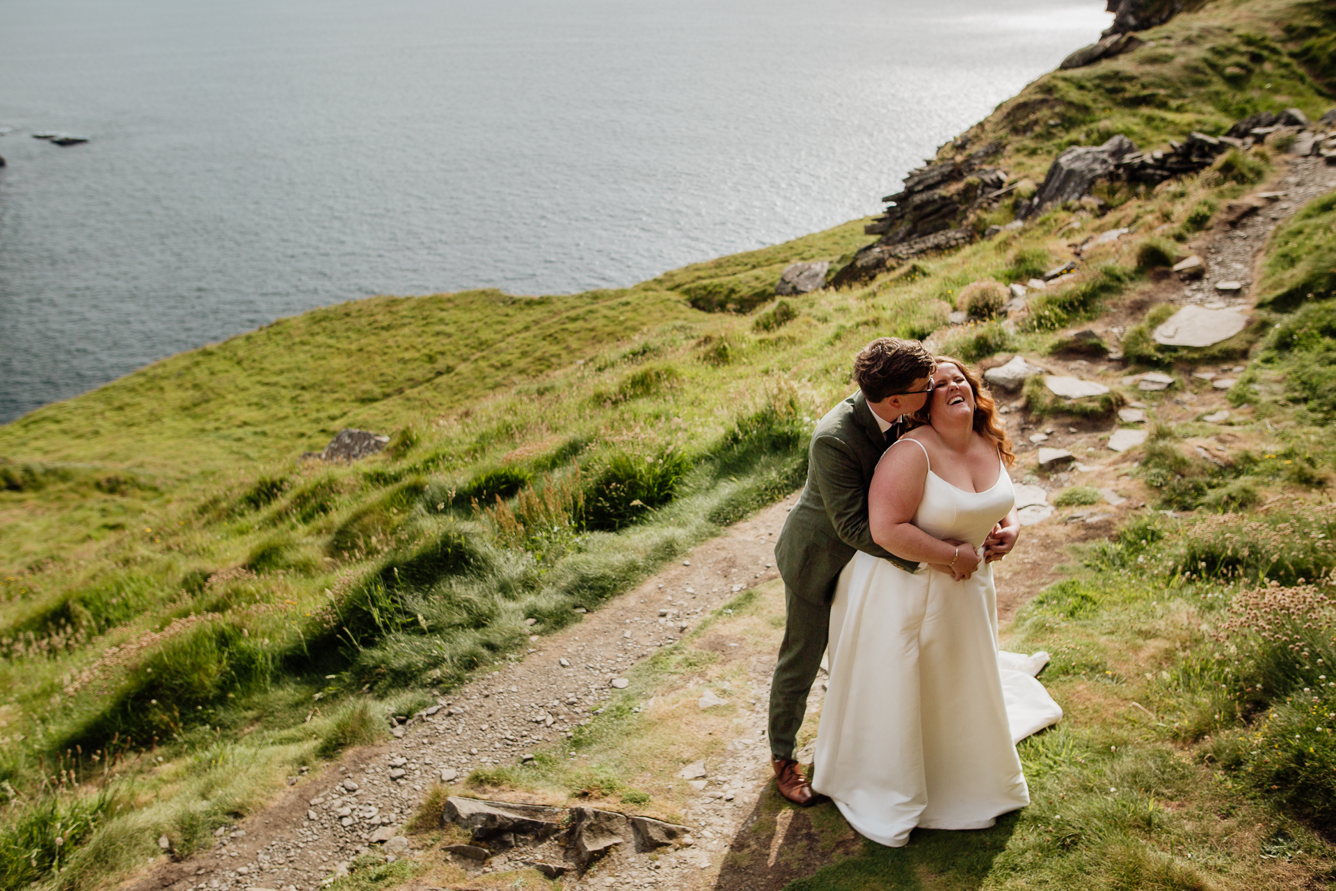 A man and woman kissing on a path by the water