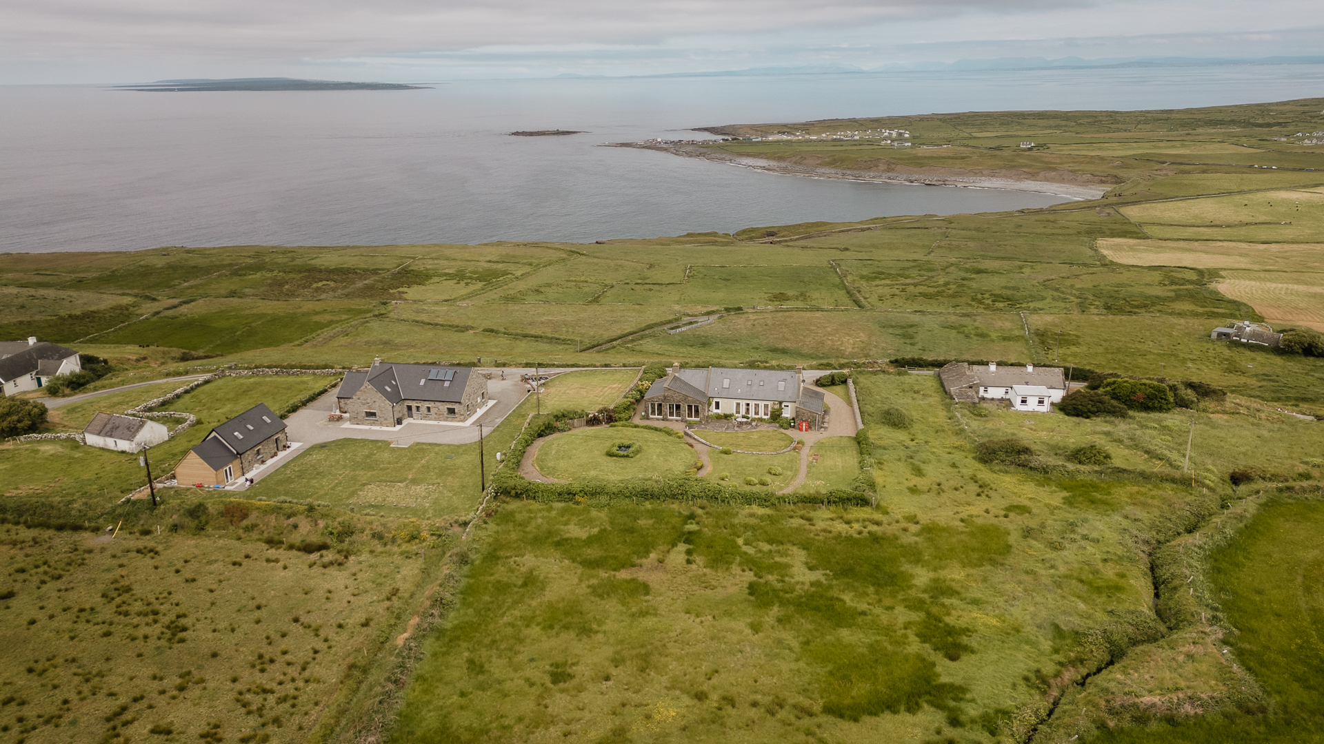 A group of houses on a grassy hill by the water