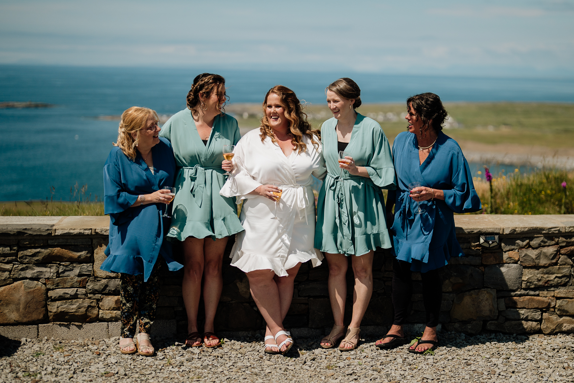 A group of women standing on a stone wall by the water