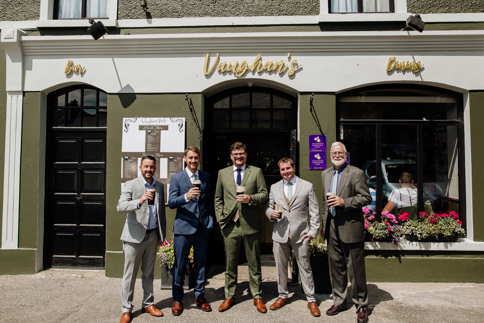 A group of men posing for a photo in front of a building