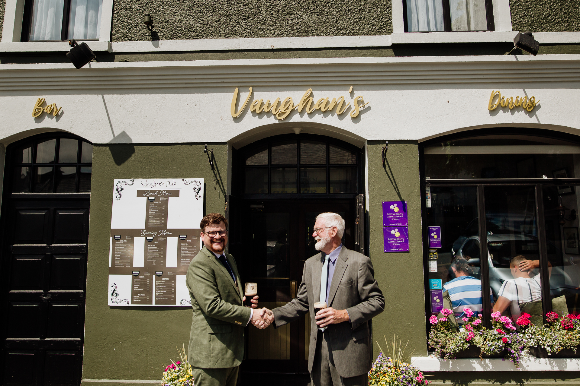 A couple of men standing in front of a building with a sign