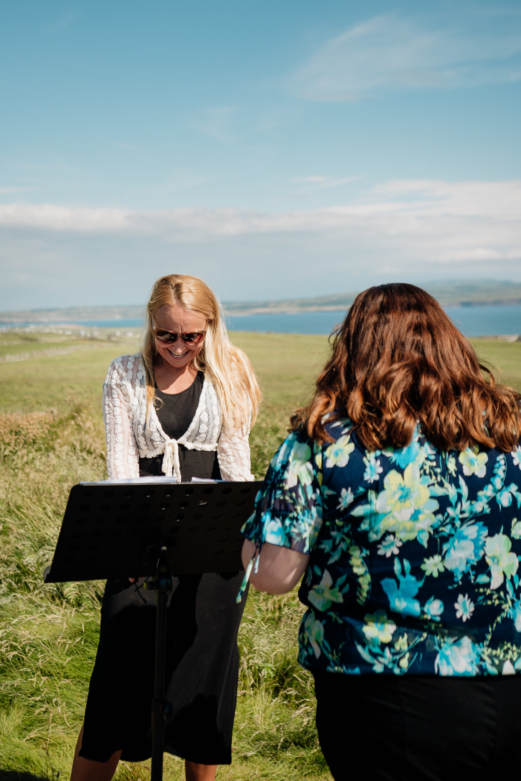 A couple of women standing on a hill with a laptop