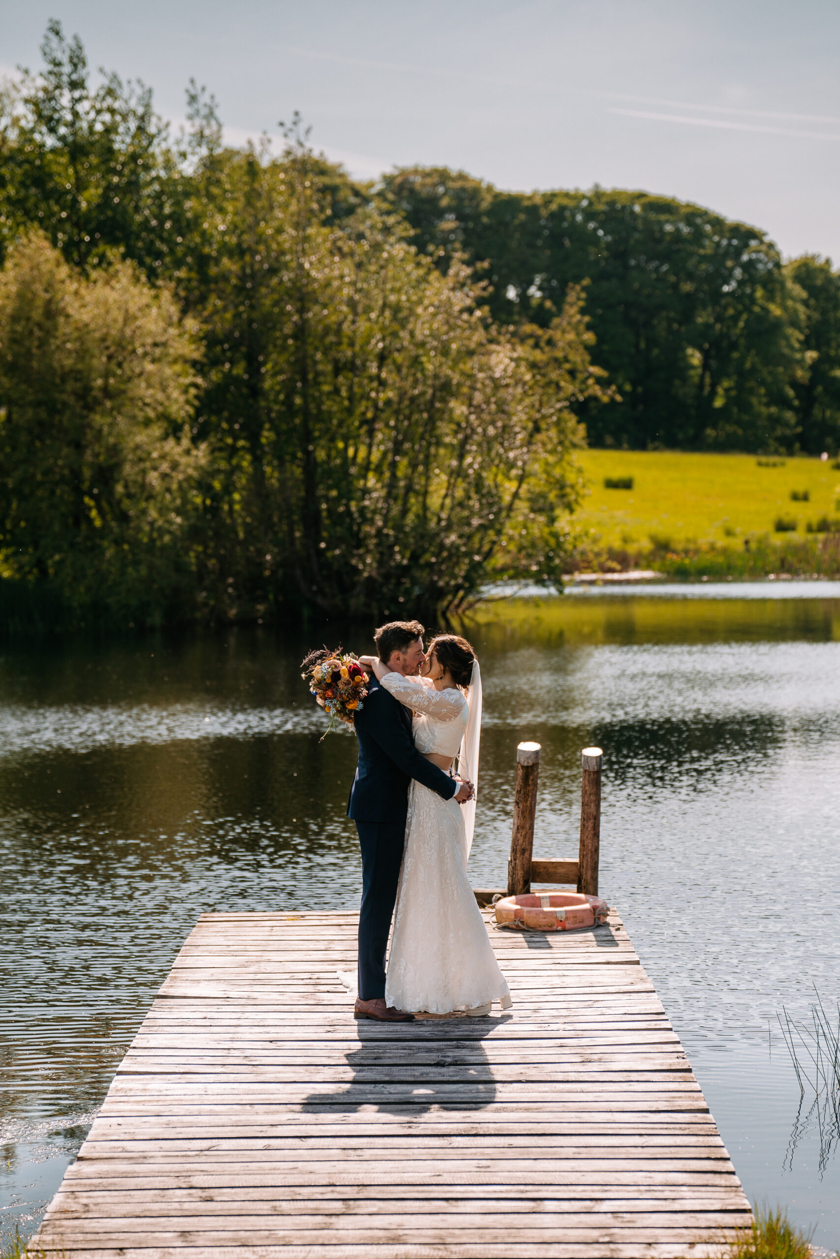 A man and woman kissing on a dock over water