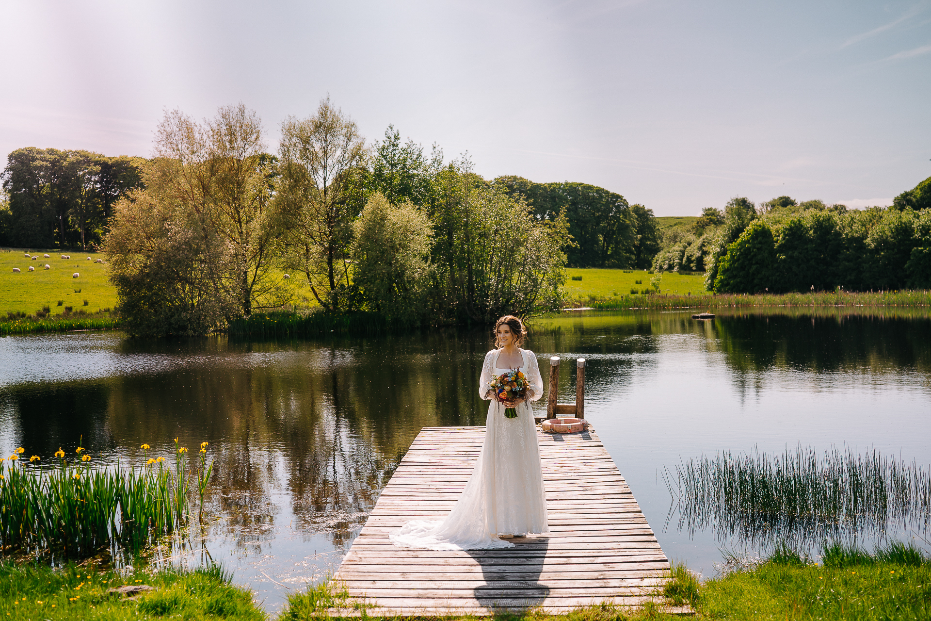 A man in a white dress standing on a dock over a body of water