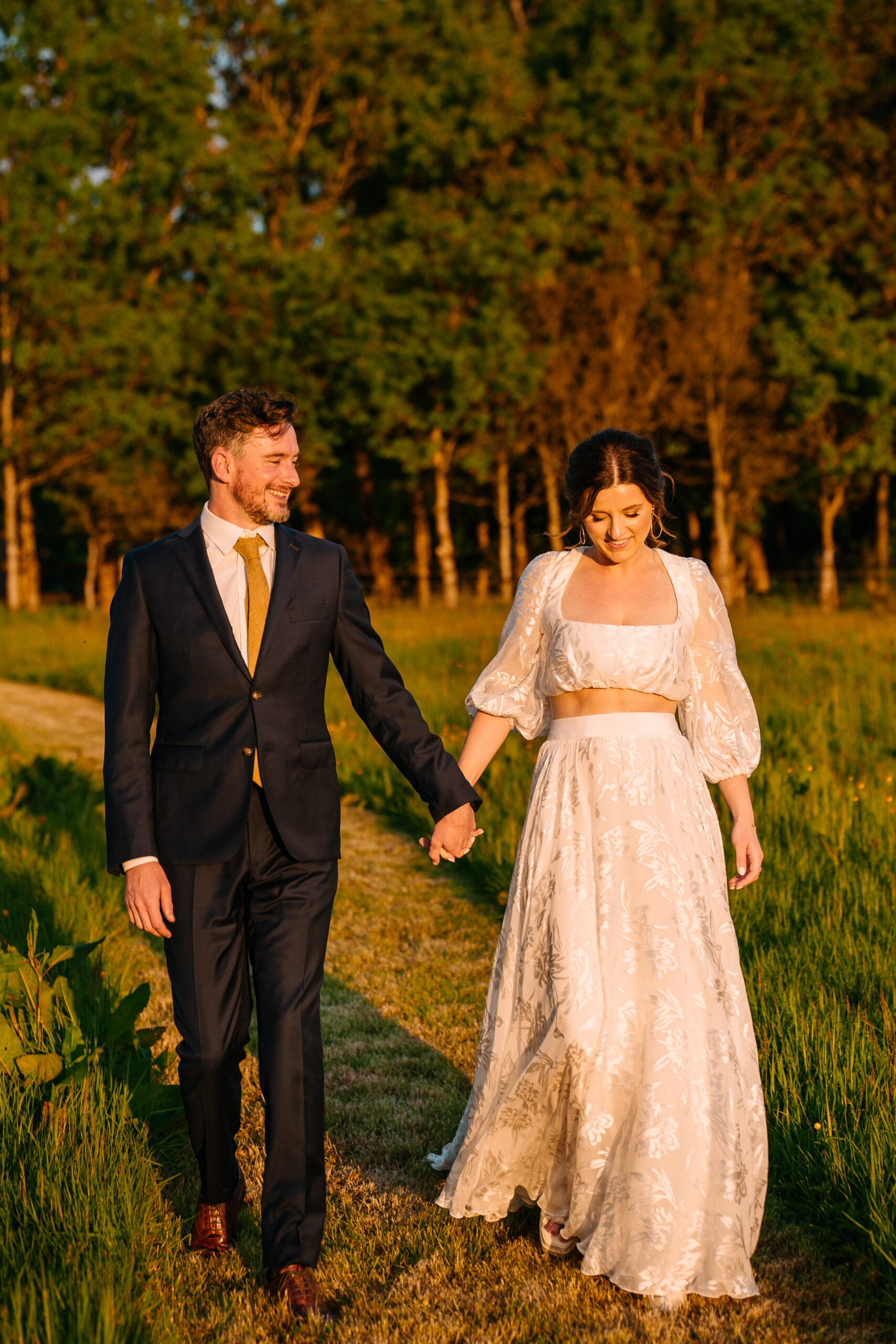 A man and woman walking down a path in a field