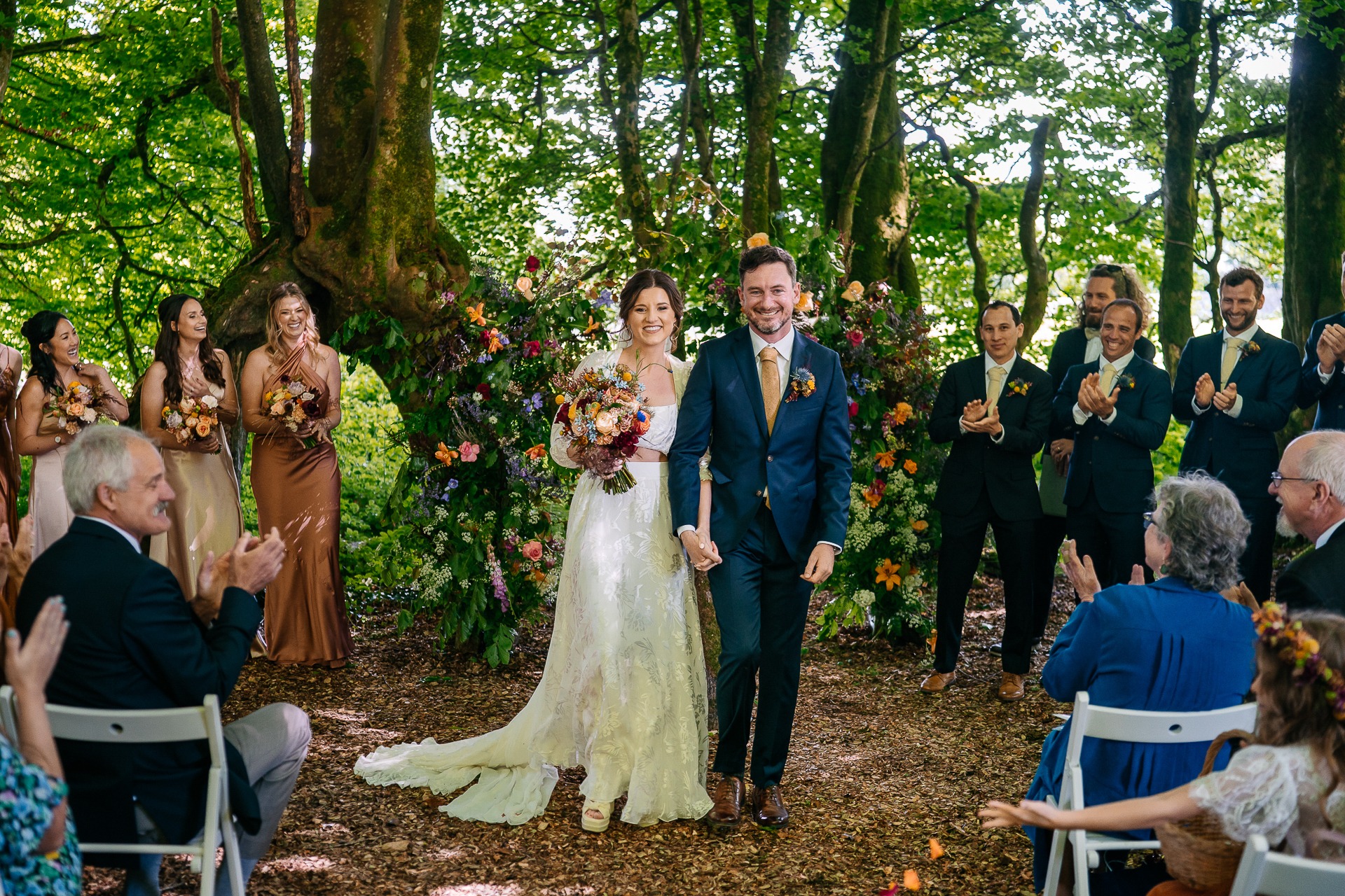 A man and woman walking down a path with people watching