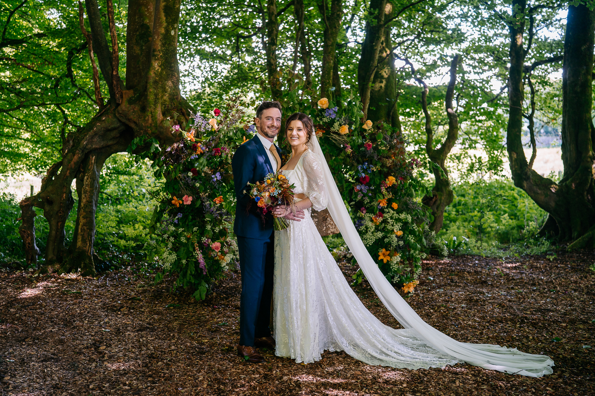 A man and woman in formal wear in a forest