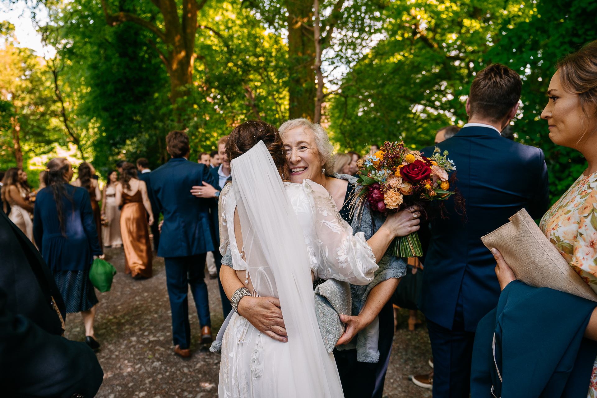 A person in a white dress holding flowers in a crowd of people